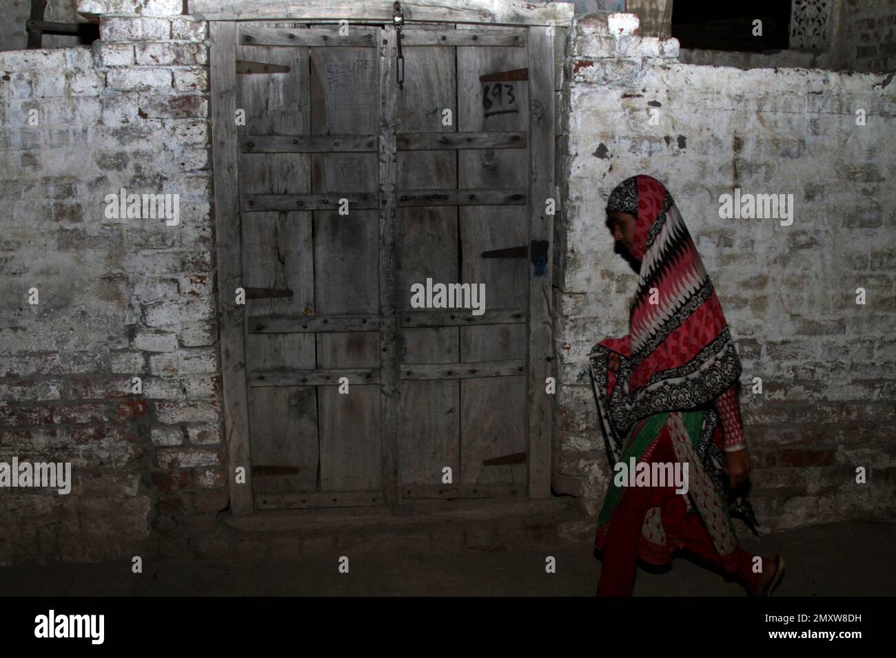 A Pakistani woman walks past a house of the Pakistani Christian boy which is locked, in district Kasur, Pakistan, Wednesday, Sept. 21, 2016. Pakistani police say they have arrested a 16-year-old Christian boy on blasphemy charges after he "liked" an "inappropriate" photograph on Facebook of the Kaaba in Mecca, one of the holiest sites in Islam. (AP Photo/K.M. Chaudary) Banque D'Images