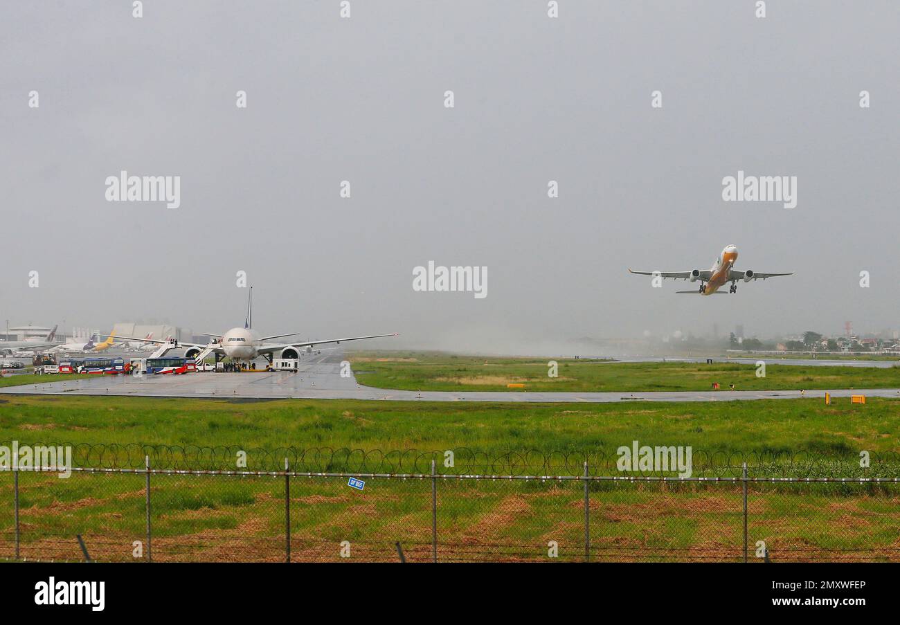 A Cebu Pacific plane takes off as a Saudi Arabian Airlines plane, left, sits on the runway of the Ninoy Aquino International Airport after making a distress call shortly before landing Tuesday, Sept. 20, 2016 at suburban Pasay city south of Manila, Philippines. Philippine officials say the Saudi Arabian Airlines plane from Jeddah was placed in isolation after it touched down, but the flight crew later said they made a mistake in sending the emergency message. Manila airport manager Eddie Monreal said authorities deployed security forces around the aircraft as a precaution. Passengers were late Banque D'Images