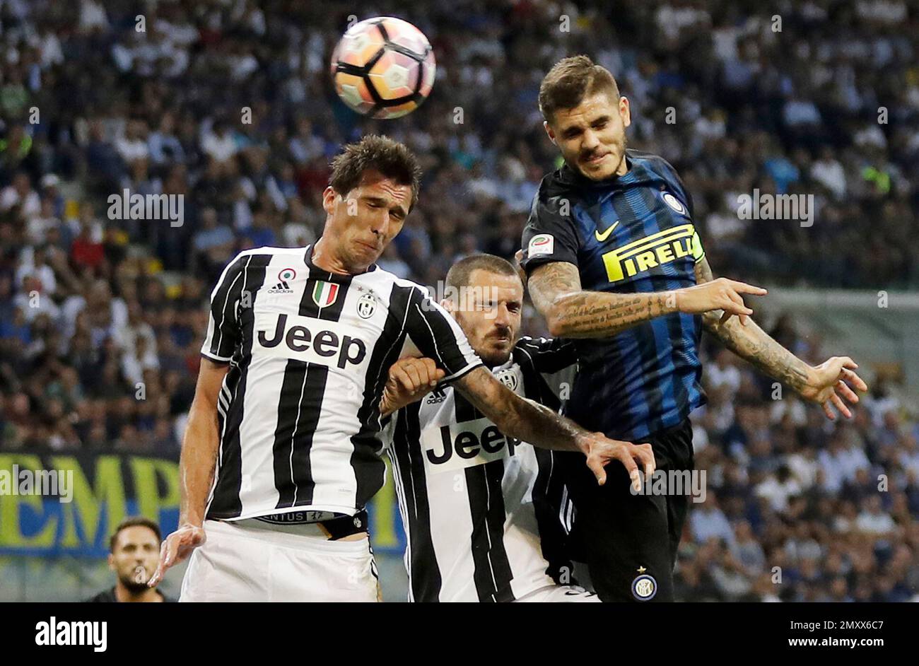 Inter Milan's Mauro Icardi, right, scores on a header past Juventus' Mario Mandzukic, left, and Leonardo Bonucci, center, during the Serie A soccer match between Inter Milan and Juventus at the San Siro stadium in Milan, Italy, Sunday, Sept. 18, 2016. (AP Photo/Antonio Calanni) Banque D'Images