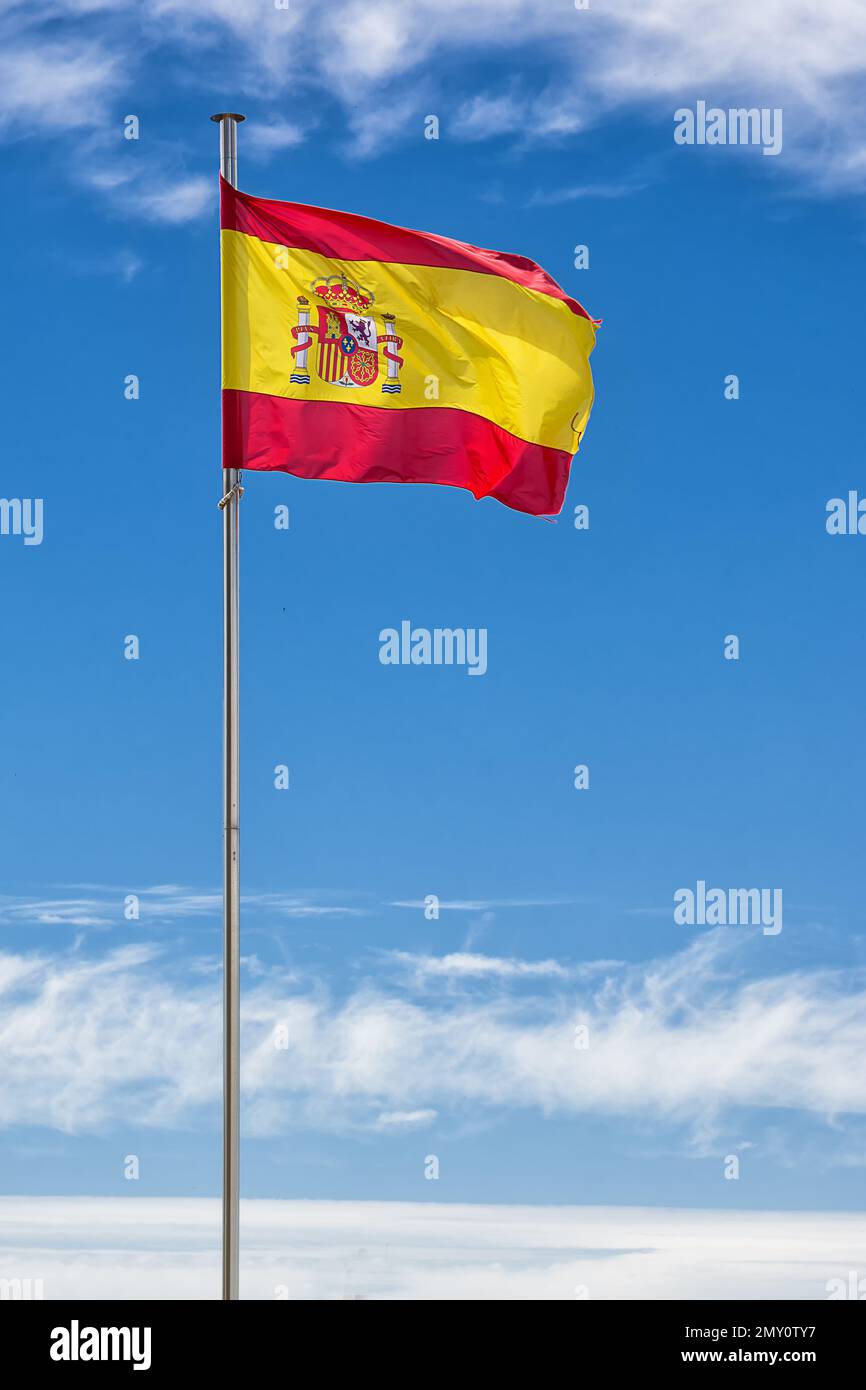 Drapeau espagnol hissé sur le mât dans le vent avec le ciel bleu Banque D'Images