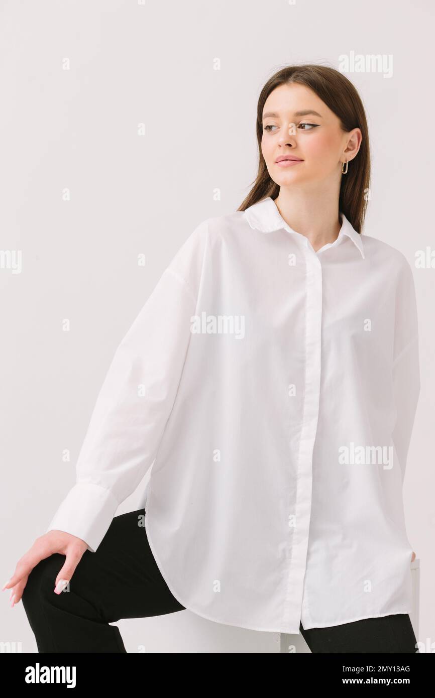 Photo d'une jolie femme dans une chemise blanche assise sur un cube blanc,  isolée sur un fond blanc. Maquette de chemise Photo Stock - Alamy