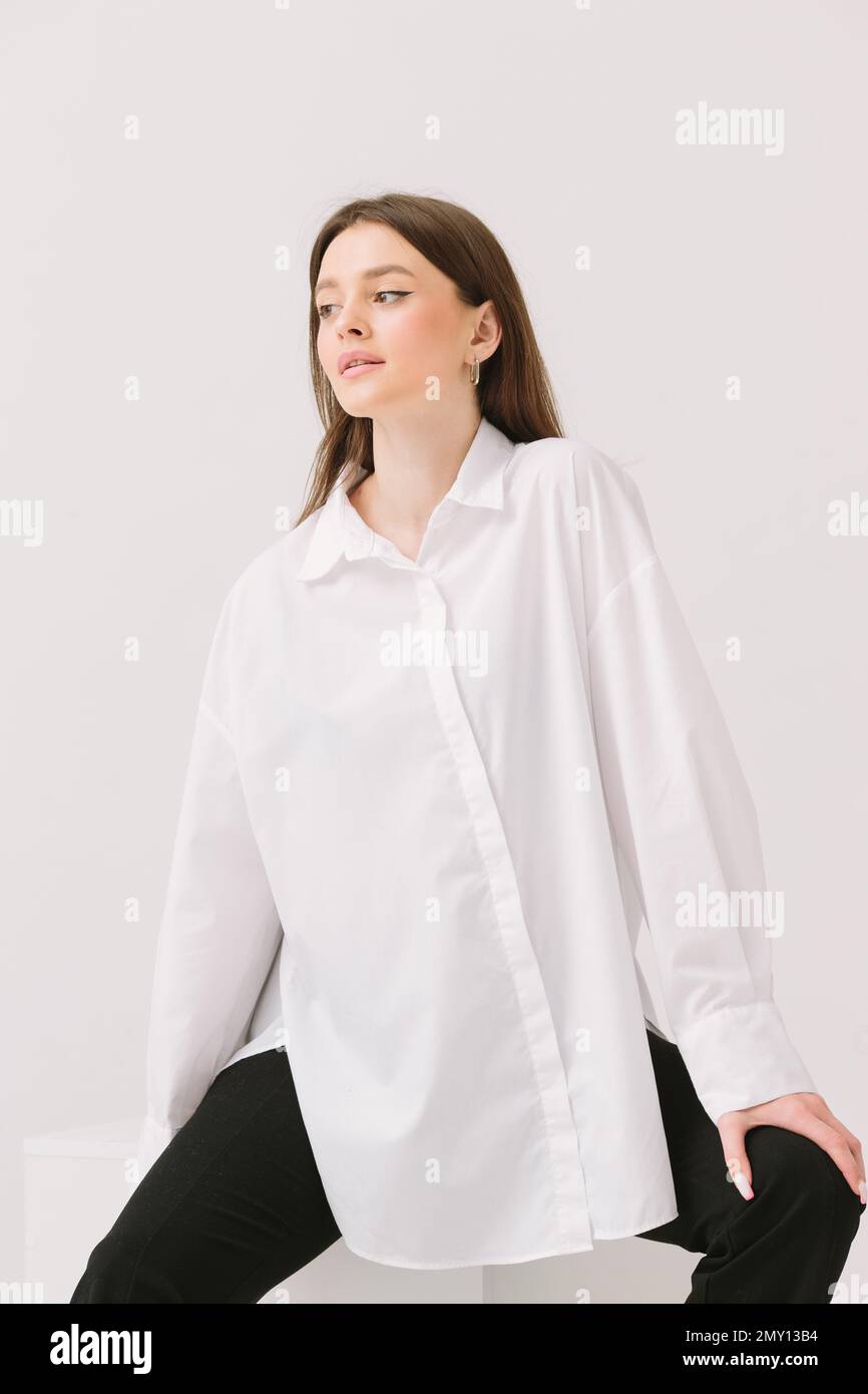 Photo d'une jolie femme dans une chemise blanche assise sur un cube blanc,  isolée sur un fond blanc. Maquette de chemise Photo Stock - Alamy