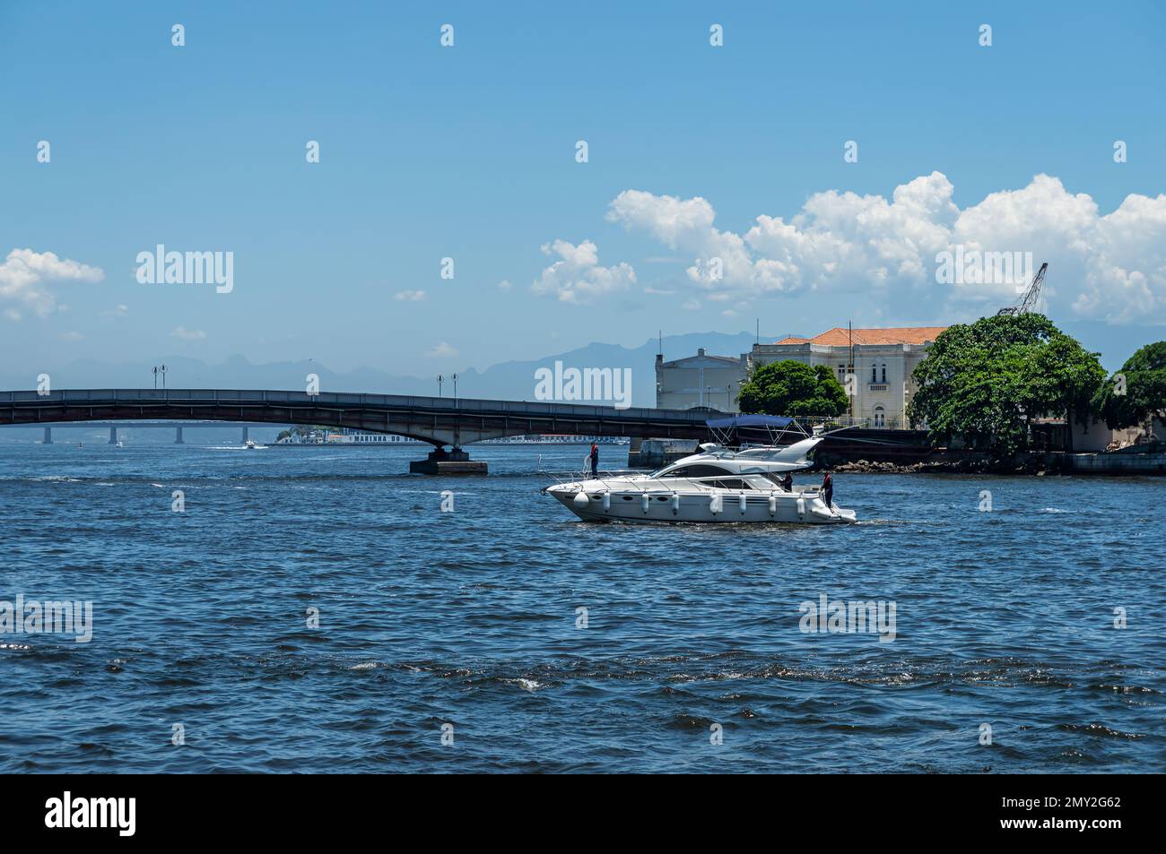 Un hors-bord blanc naviguant sur les eaux de la baie de Guanabara dans le quartier du Centro avec le pont Arnaldo Luz à l'arrière-midi d'été ensoleillé ciel clair Banque D'Images