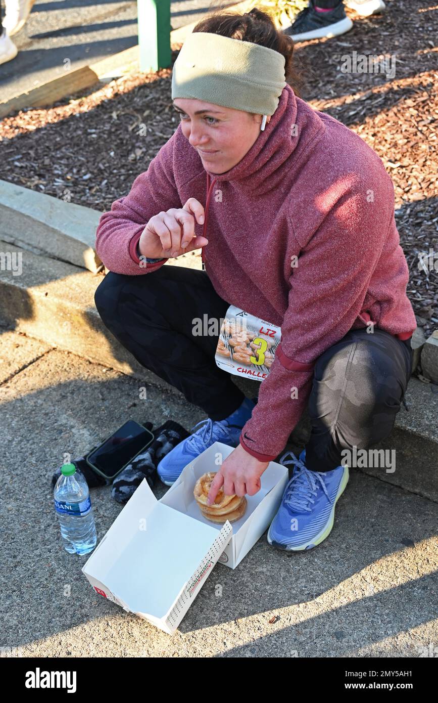 Raleigh, NC, USA, 4th février 2023, Runners Wolf Down une douzaine de beignes Krispy Kreme à mi-chemin d'un sprint de 5 km du campus de l'université d'État de Caroline du Nord. Première course en 2004 comme une ose parmi les amis, le défi annuel Krispy Kreme est rapidement devenu un collecteur de fonds au profit de l'Hôpital pour enfants de l'UNC. Le parcours de 28:29 a été établi en 2020 avec un rythme de 5:41/mile, ce qui inclut le temps de manger des beignets. Avec une exposition nationale, la devise est « 2 400 calories, 12 beignets, 5 miles, 1 heures ». Credit D Guest Smith / Alamy Live News Banque D'Images