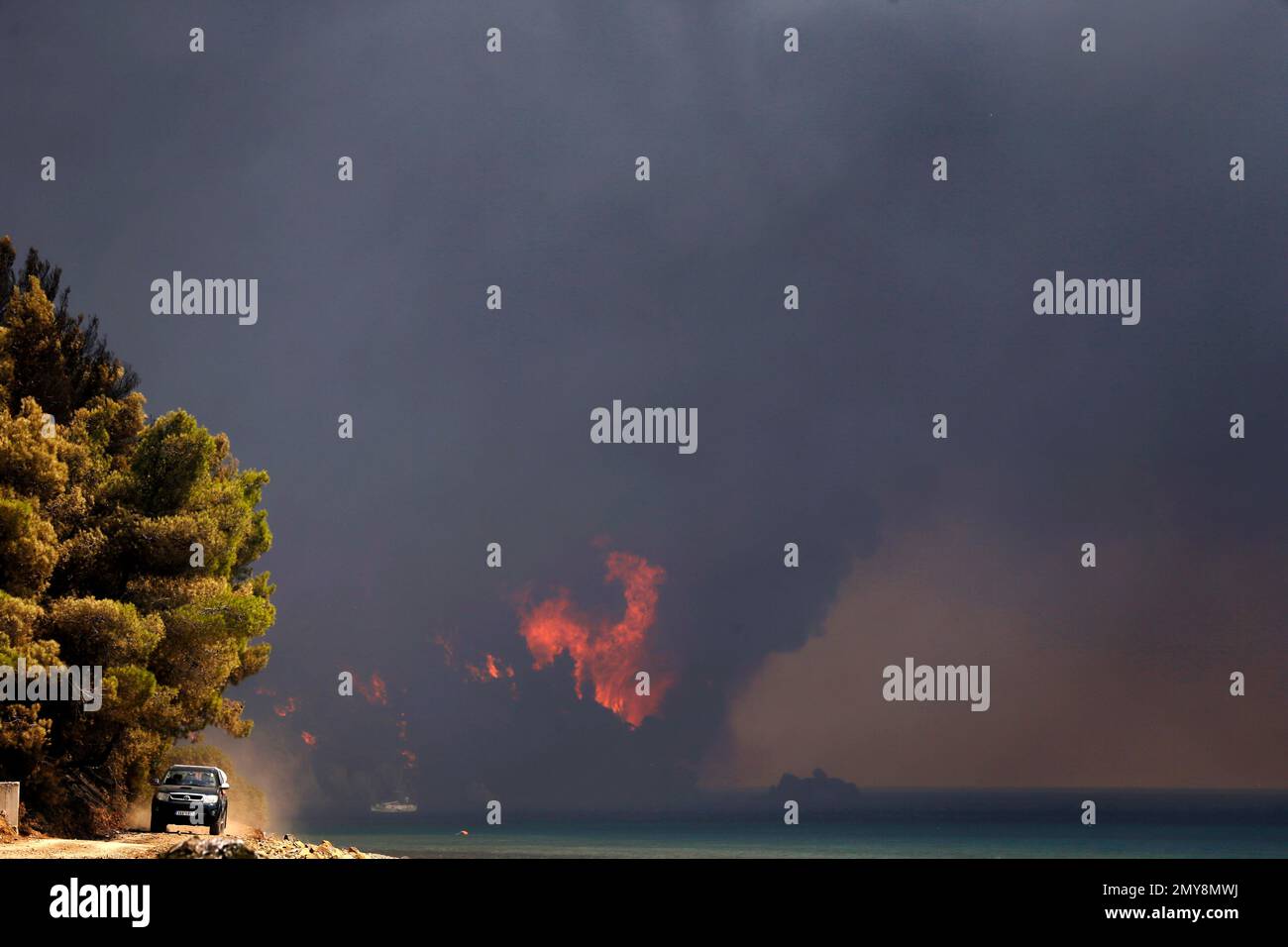 A local resident drives his car next to the beach as a fire burns a forest over the sea near the village of Limni on the island of Evia, about 160kilometers (100 miles) north of Athens, Monday, Aug. 1, 2016. Nearly 200 firemen, assisted by water-dropping aircraft, fire engines and volunteers, are fighting a large forest fire that has raged through the Greek island of Evia for the past three days (AP Photo/Thanassis Stavrakis) Banque D'Images