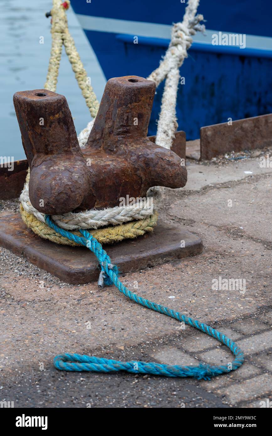 Vieux bollard d'amarrage en métal rouillé avec des couleurs différentes roppé attaché autour d'elle au quai de carrossage, Portsmouth, Angleterre. Banque D'Images