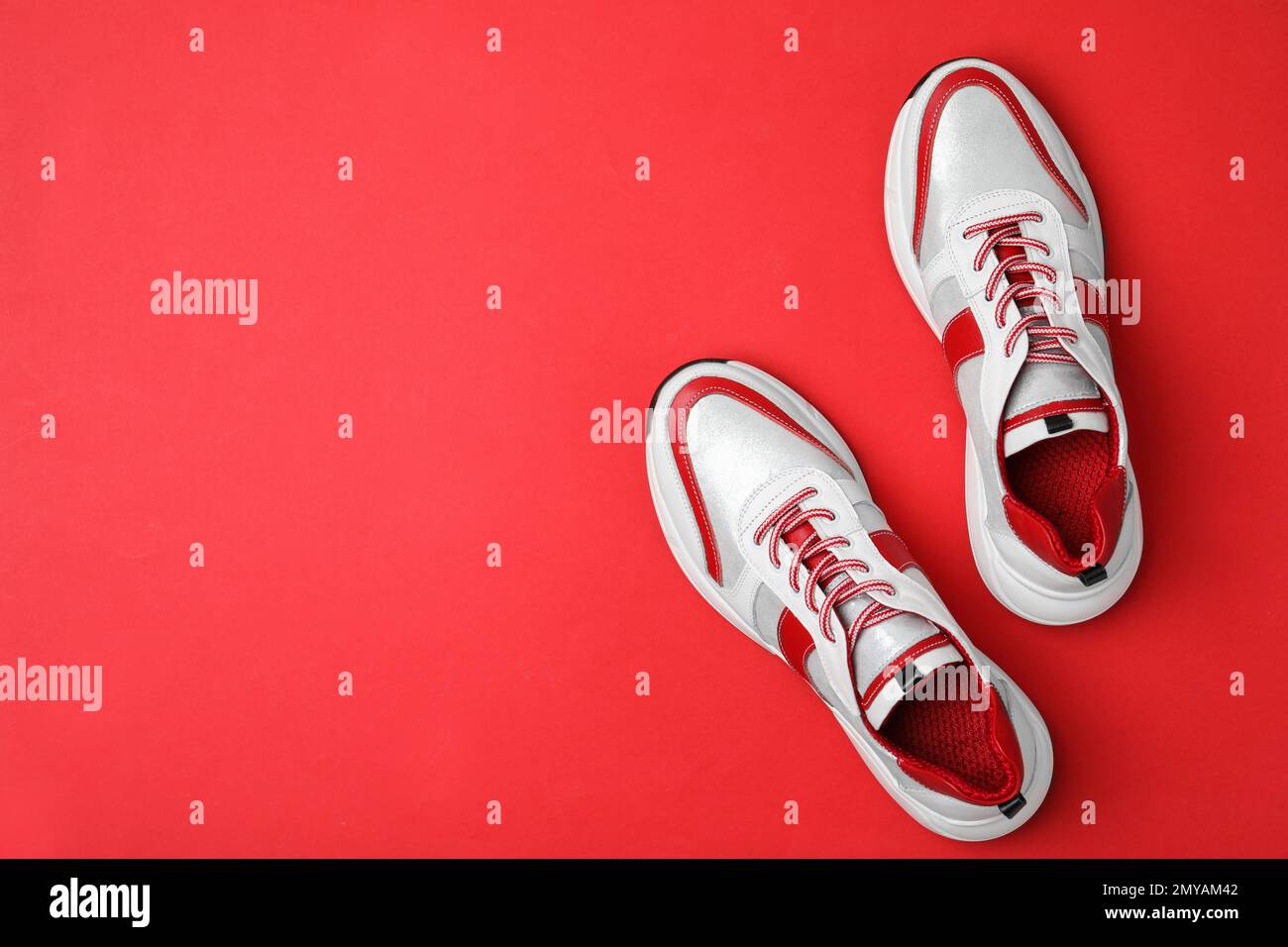 Baskets élégantes sur fond rouge, sans lacets. Espace pour le texte Banque D'Images
