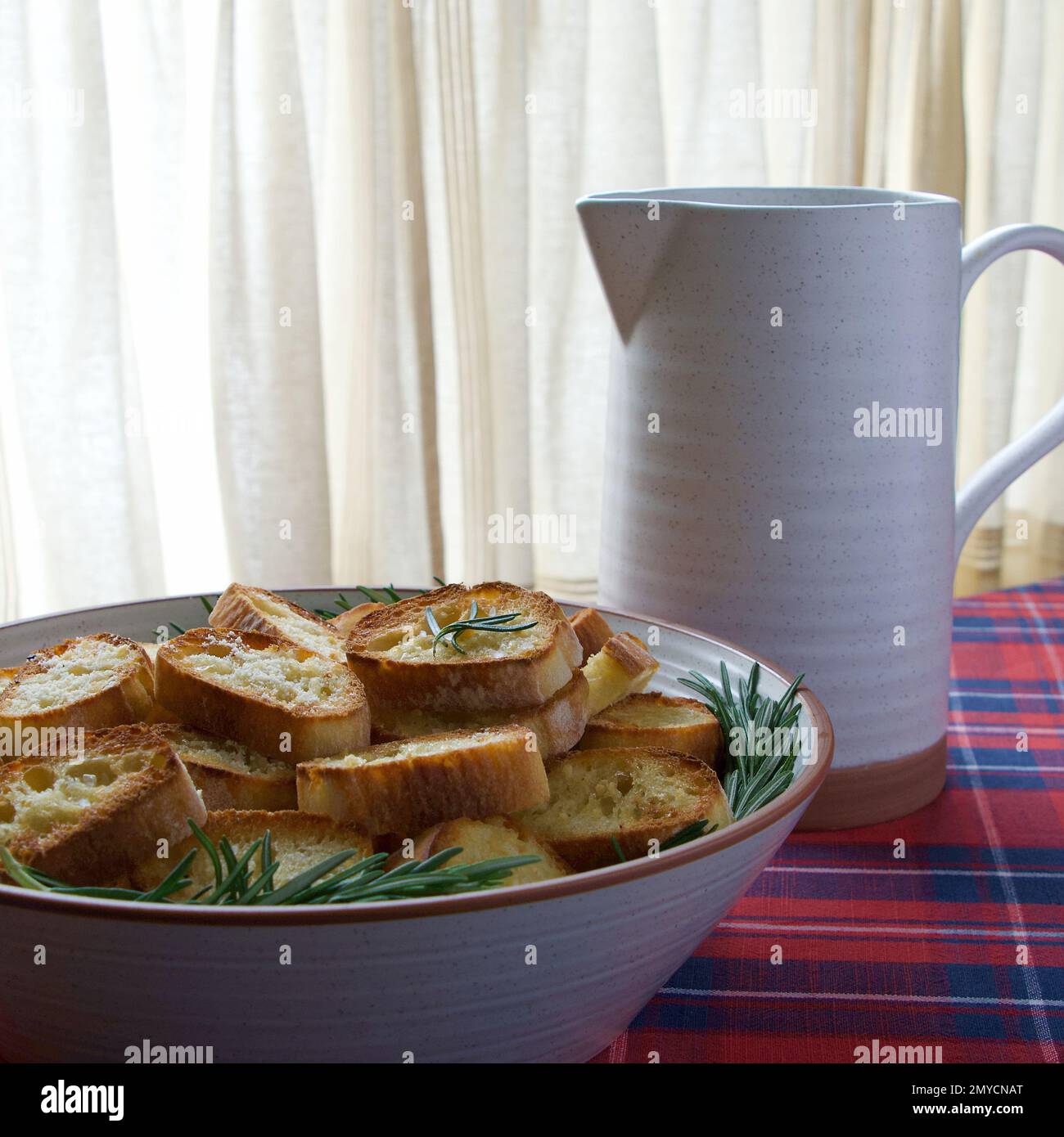 Bol de tranches de pain grillées au romarin et un pichet Banque D'Images