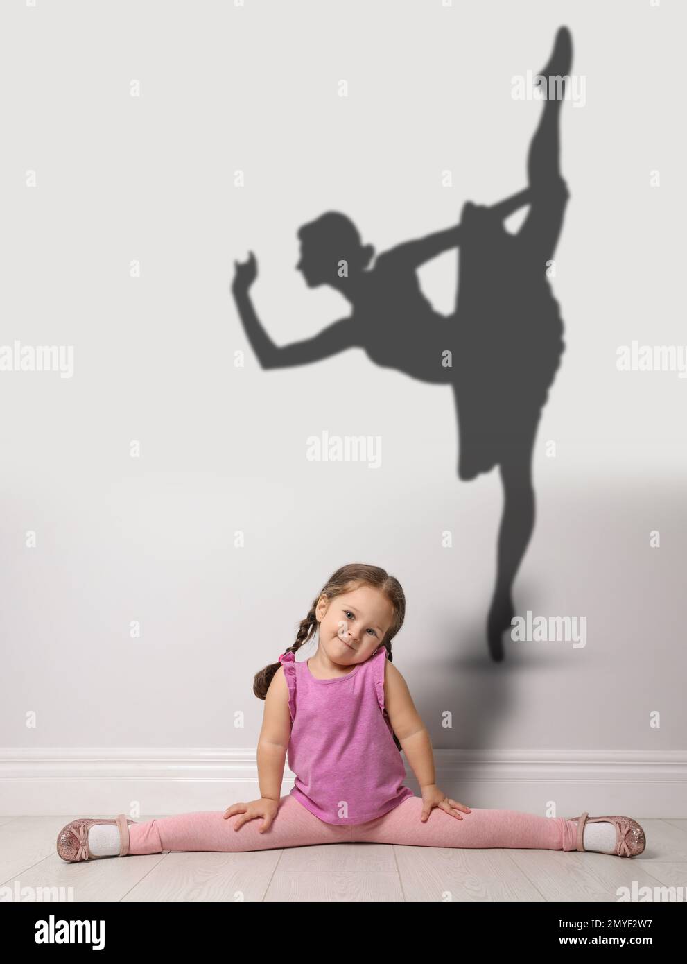 Petite fille mignonne rêvant d'être danseuse de ballet. Silhouette de femme derrière le dos de l'enfant Banque D'Images