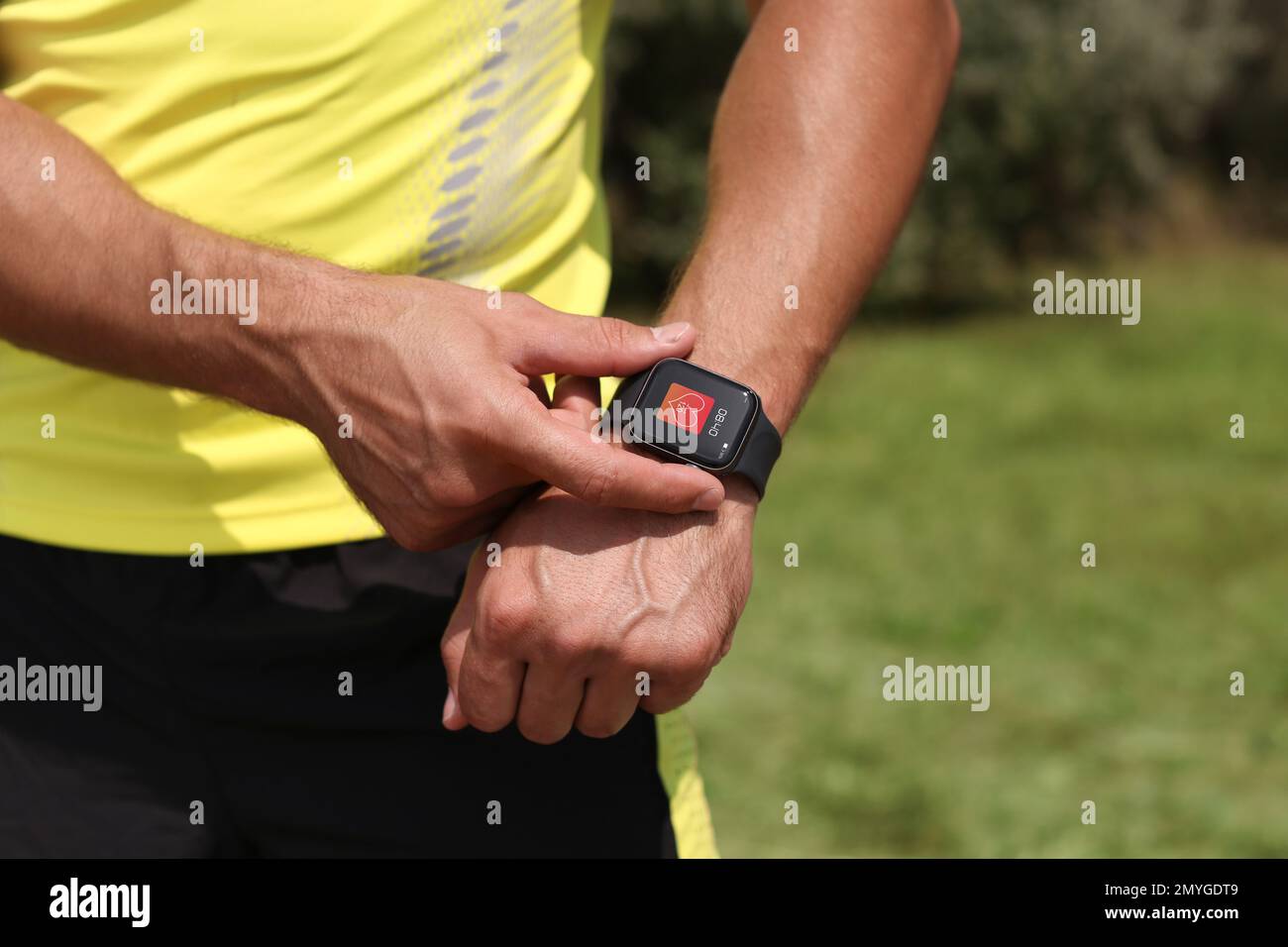 Homme avec une montre intelligente qui vérifie la fréquence cardiaque dans l'application de surveillance de la santé à l'extérieur, gros plan Banque D'Images