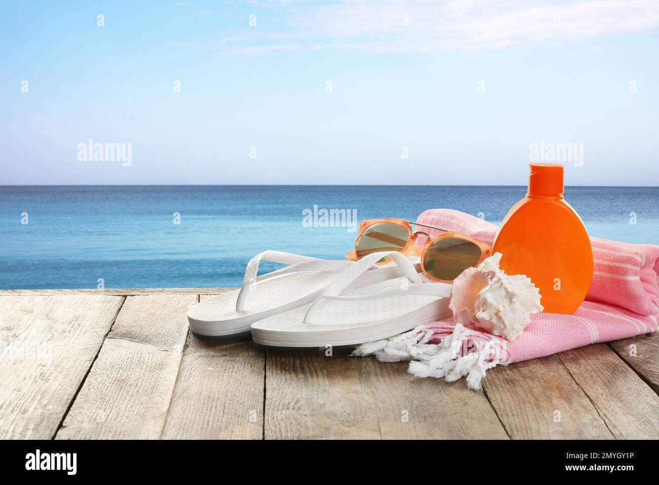 Accessoires de plage sur une surface en bois près de la mer, espace pour le texte Banque D'Images