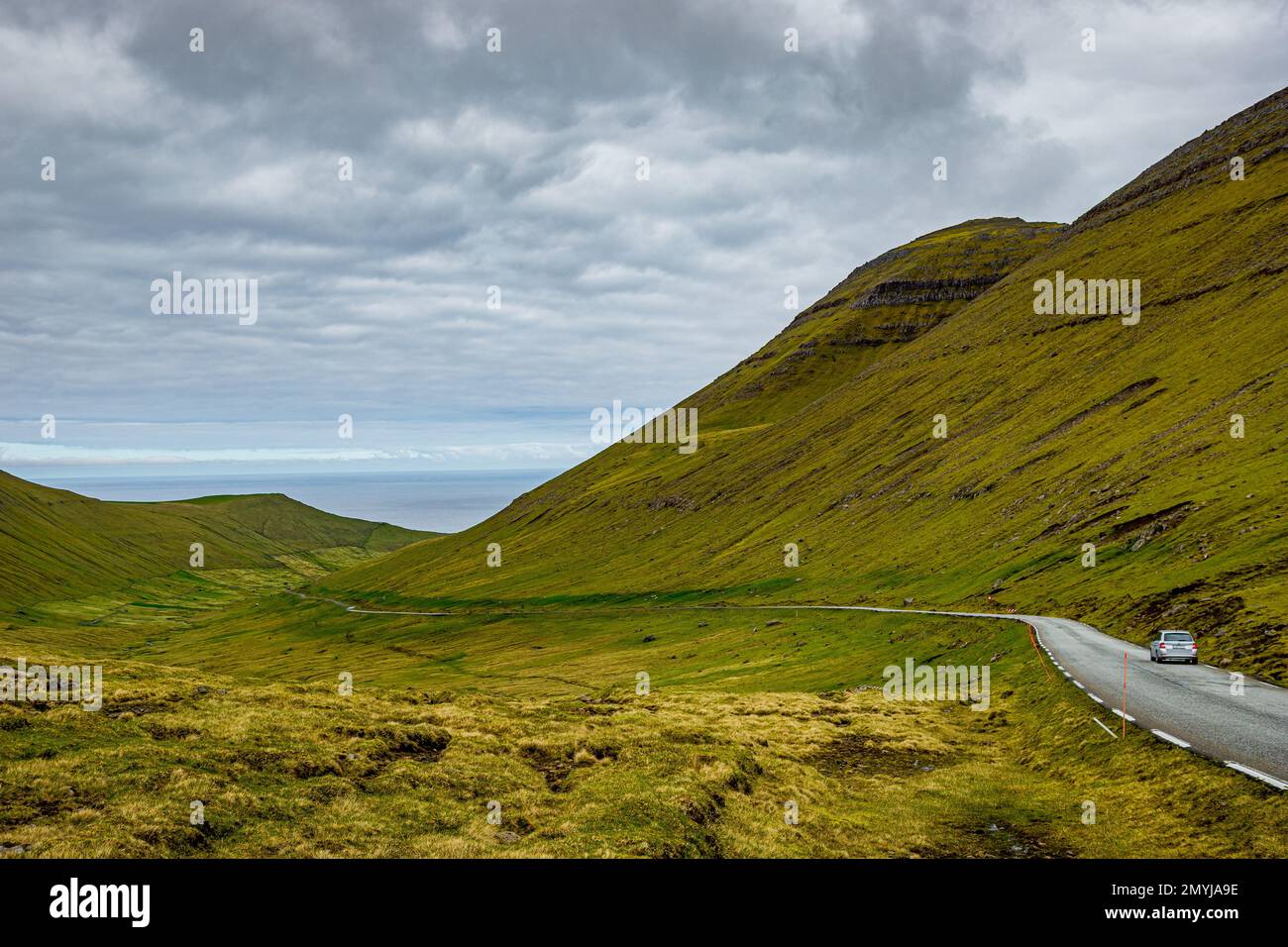 Route étroite au col du village de Gjogv avec voiture dans la vallée herbeuse sur l'île d'Eysturoy dans les îles Féroé Banque D'Images