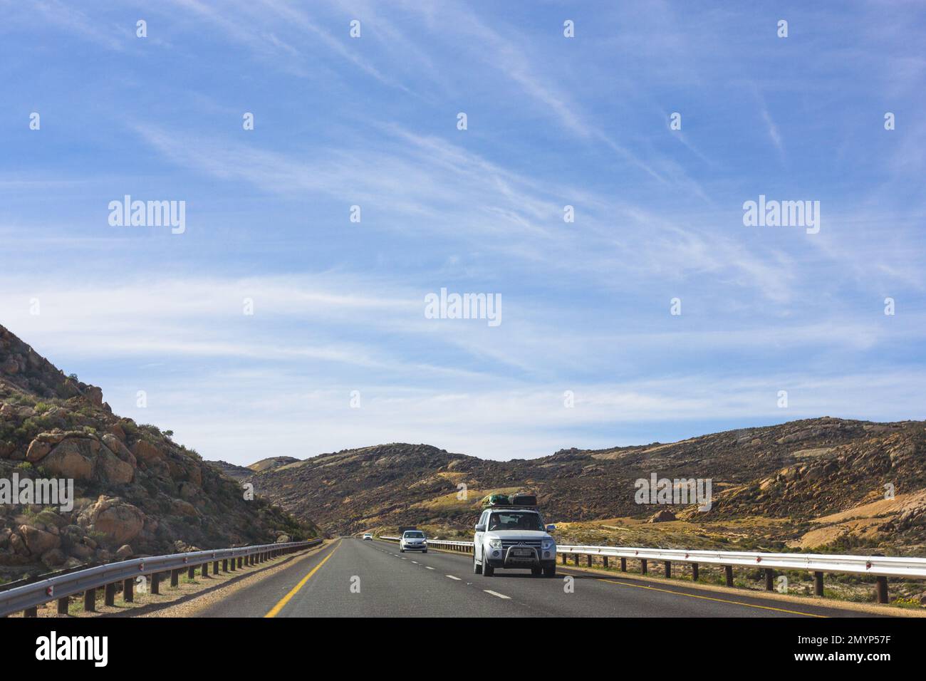 Voyage en voiture ou route à travers Namaqualand, Afrique du Sud montrant le paysage aride et une longue route nationale droite avec des véhicules et un 4x4 Banque D'Images