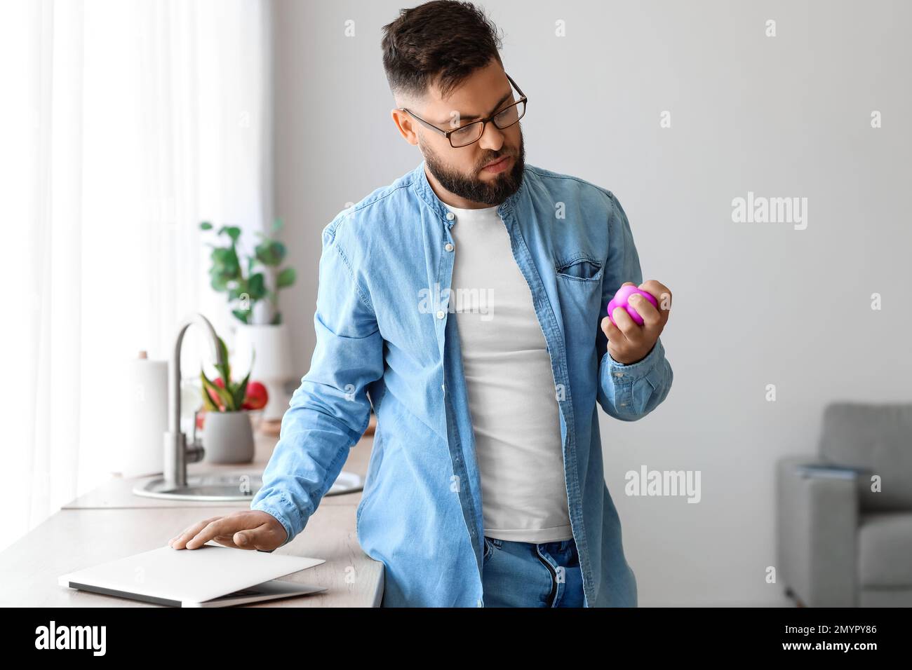 Un jeune homme stressé se met à presser le ballon à la maison Banque D'Images
