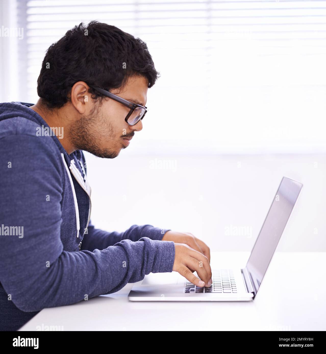 Obtenir son diplôme par correspondance. un beau jeune homme qui travaille sur son ordinateur portable dans un bureau. Banque D'Images