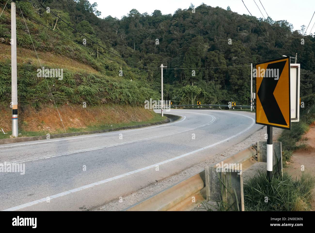 Le panneau de signalisation indique un virage serré devant une rue vide. Banque D'Images