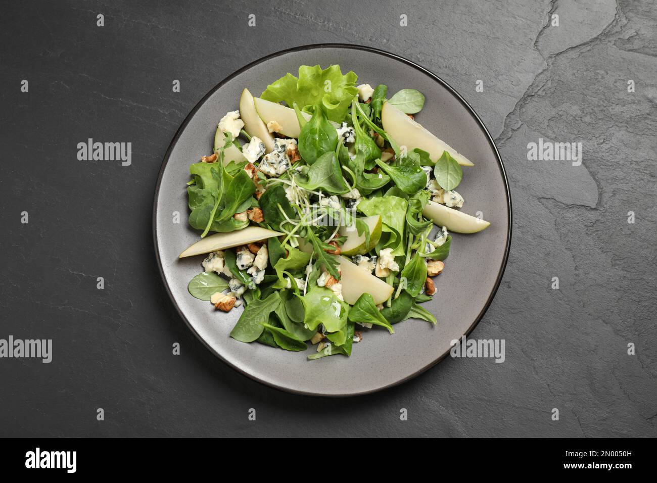 Salade savoureuse avec tranches de poire sur table noire, vue du dessus Banque D'Images