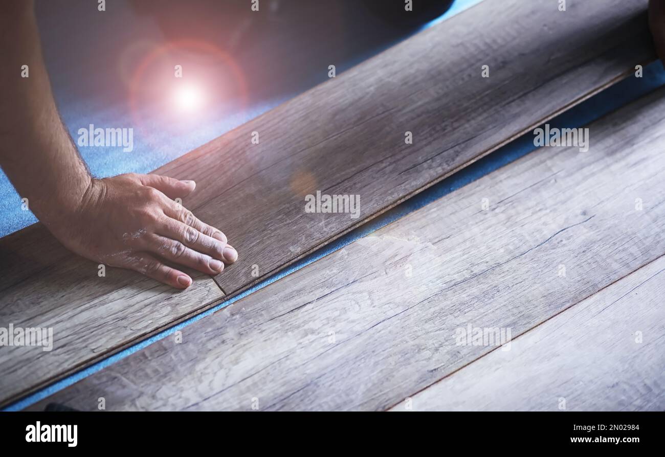 Installation de plancher laminé, détails sur les mains d'homme tenant des carreaux de bois, sur la couche de base en mousse blanche, petite pile avec plus de tuiles arrière-plan Banque D'Images