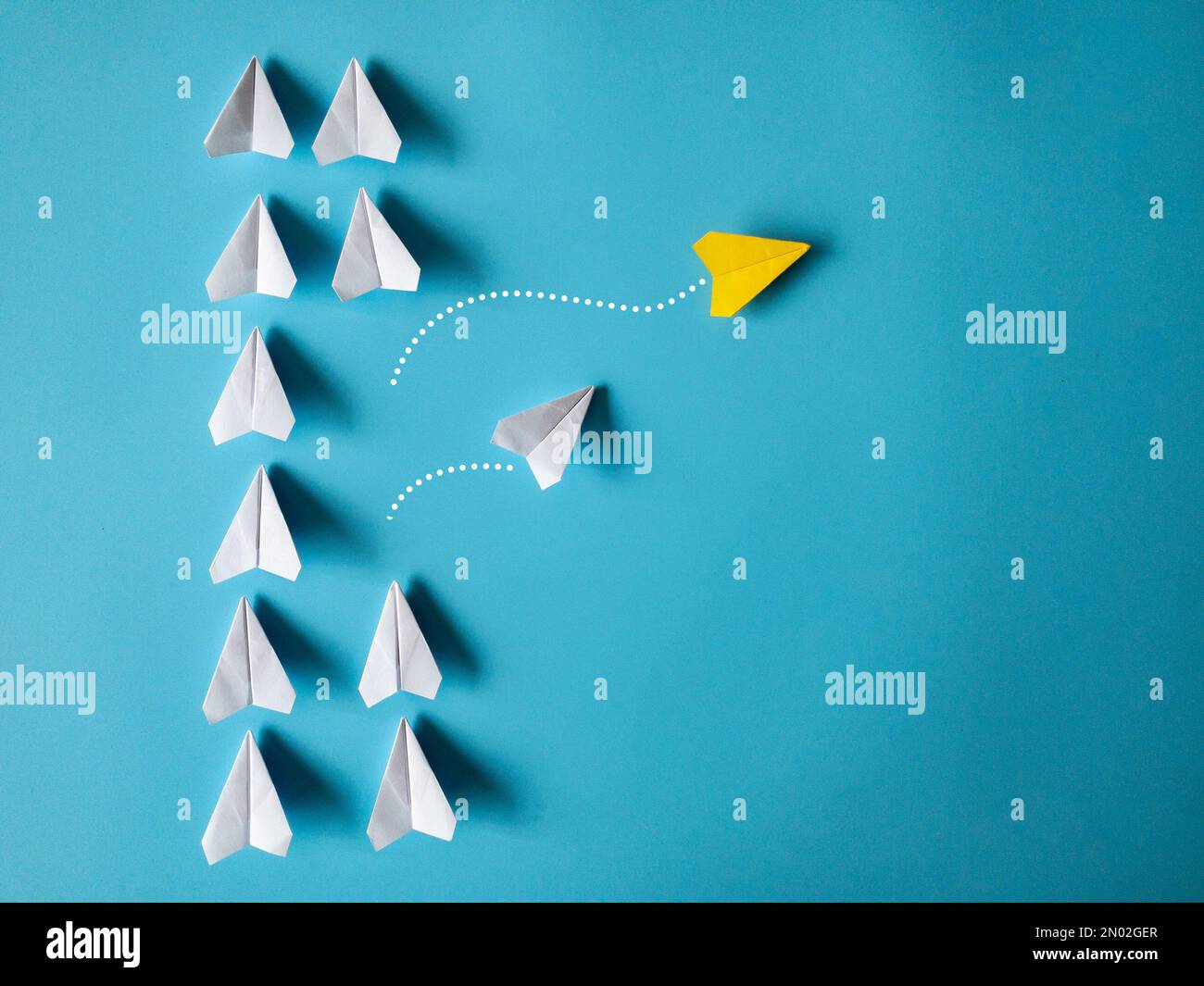 Avions à papier jaune et blanc origami laissant d'autres avions blancs sur fond bleu avec espace personnalisable pour le texte. Concept de compétences en leadership. Banque D'Images