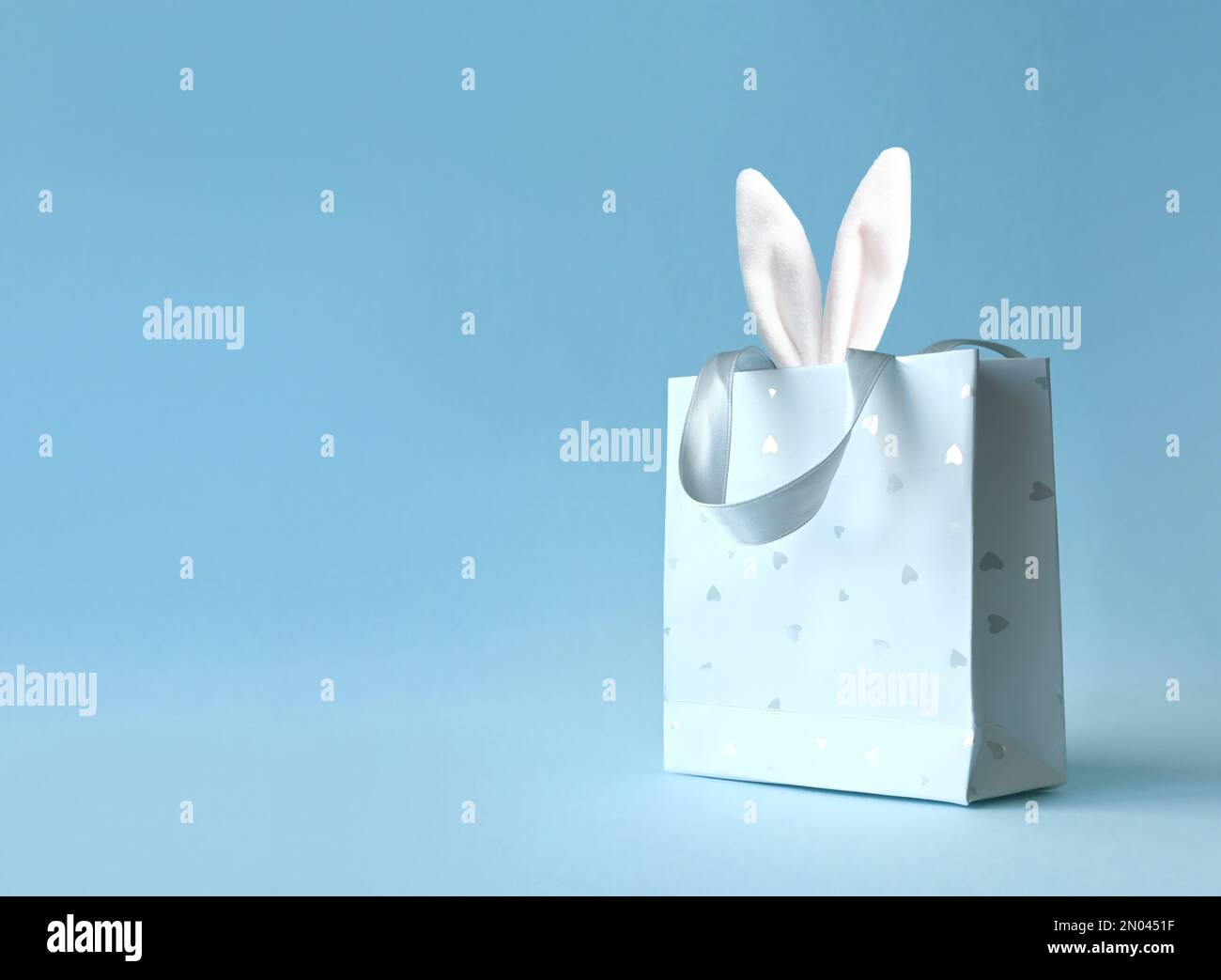 Oreilles de lapin de Pâques dans un sac en papier. Arrière-plan bleu. Espace pour le texte. Joyeuses pâques Banque D'Images