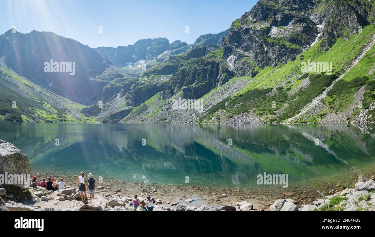 Groupe de touristes appréciant paysage alpin tout en se refroidissant sur la rive du lac vierge, Pologne, UE Banque D'Images