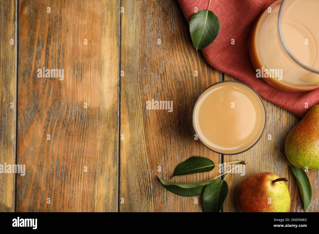 Savoureux jus de poire, fruits et feuilles sur table en bois, plat. Espace pour le texte Banque D'Images