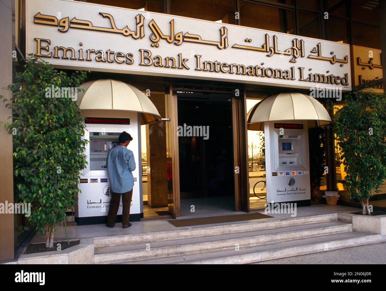 Dubai UAE Man Using ATM Outside Emirates Bank International Limitied Banque D'Images