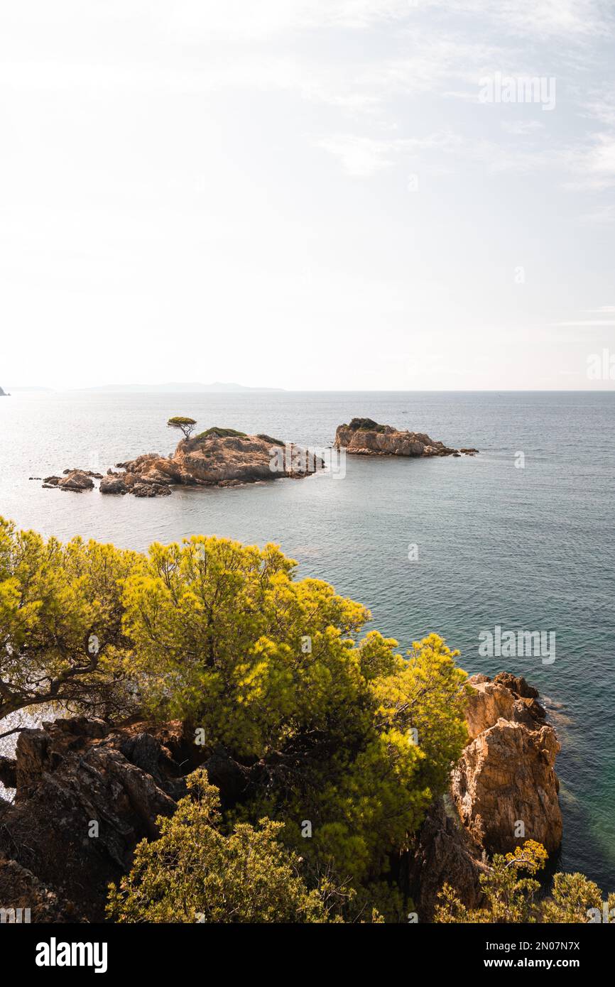 Une falaise rocheuse avec deux petites îles en arrière-plan, juste au large de la côte de Bormes-les-Mimosas, France Banque D'Images