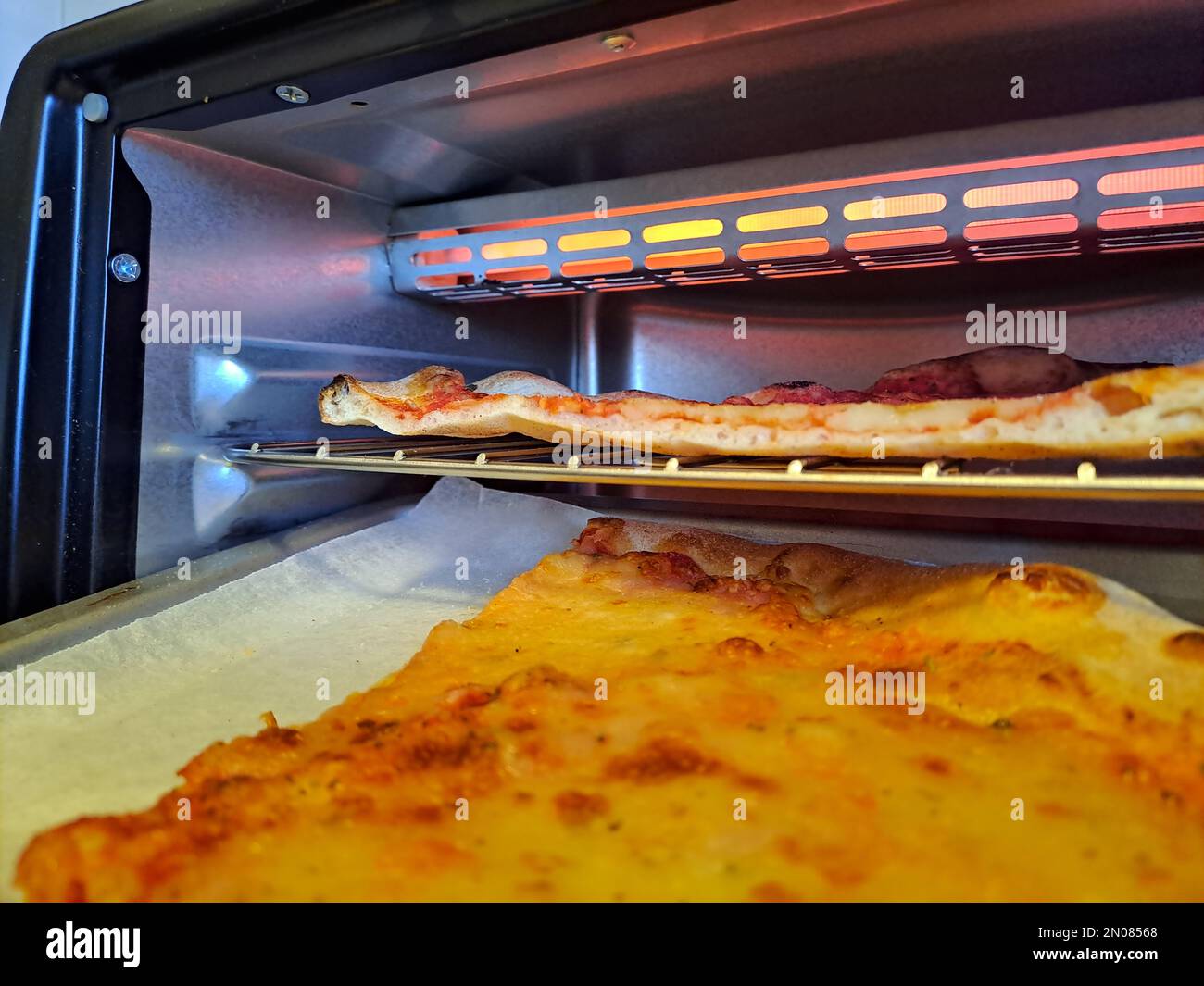 Tranche de pizza au fromage gros plan la vie réelle dans la cuisine, réchauffez dans le four électrique Banque D'Images