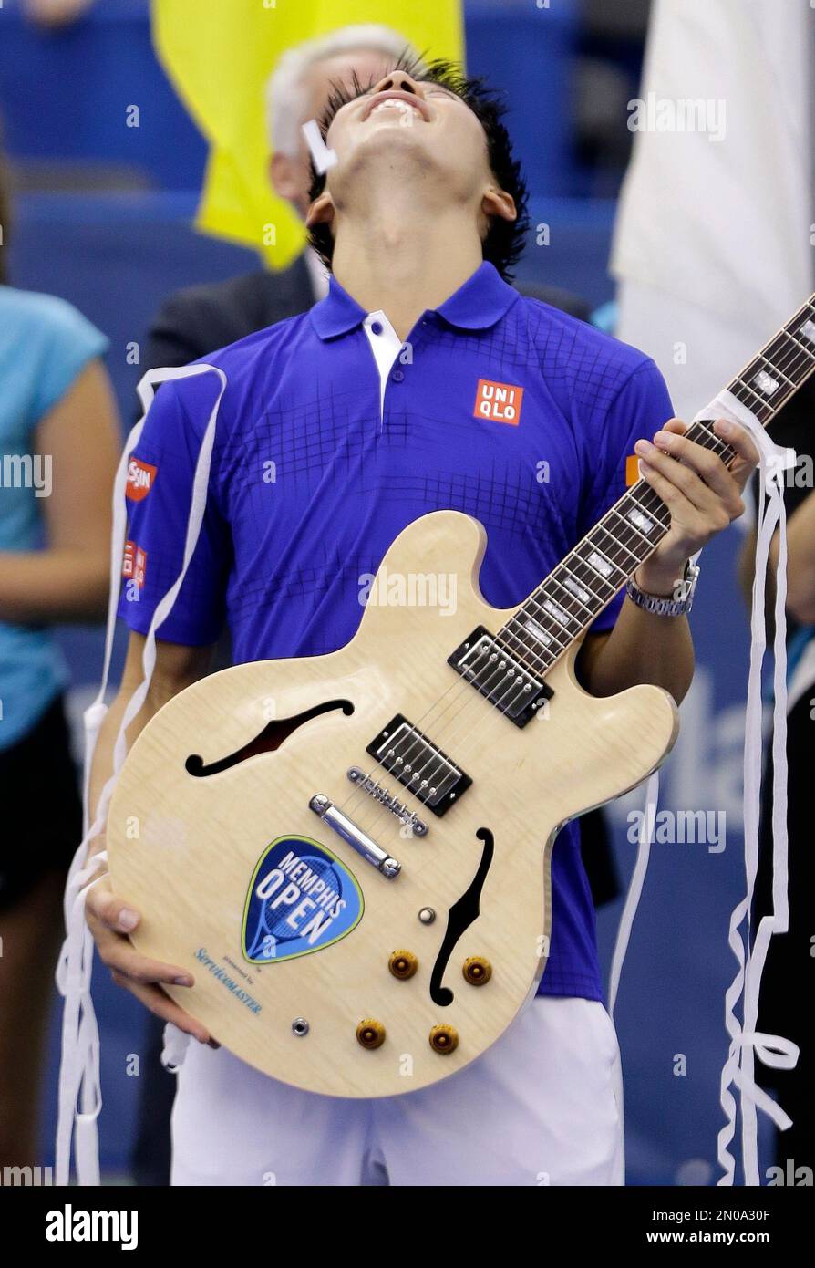 Kei Nishikori of Japan holds his guitar trophy as he looks up at falling confetti after beating Taylor Fritz of the United States in the singles championship at the Memphis Open tennis tournament Sunday, Feb. 14, 2016, in Memphis, Tenn. Nishikori won 6-4, 6-4. (AP Photo/Mark Humphrey) Banque D'Images