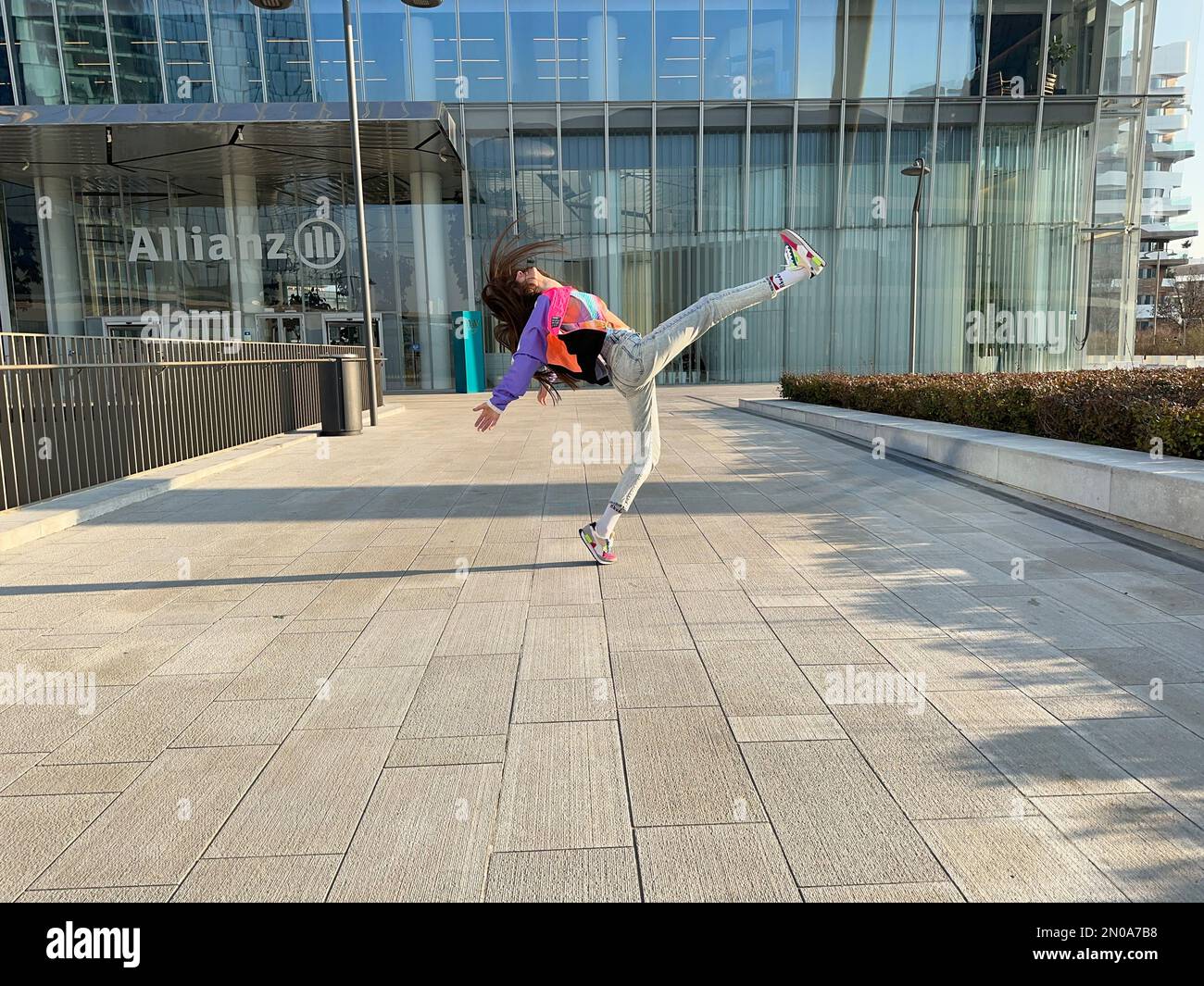 Une image fantastique d'une jeune fille, dansant dans des vêtements à la mode, sous la tour CityLife Allianz, la tour Isozaki, CityLife, Milan, Italie Banque D'Images