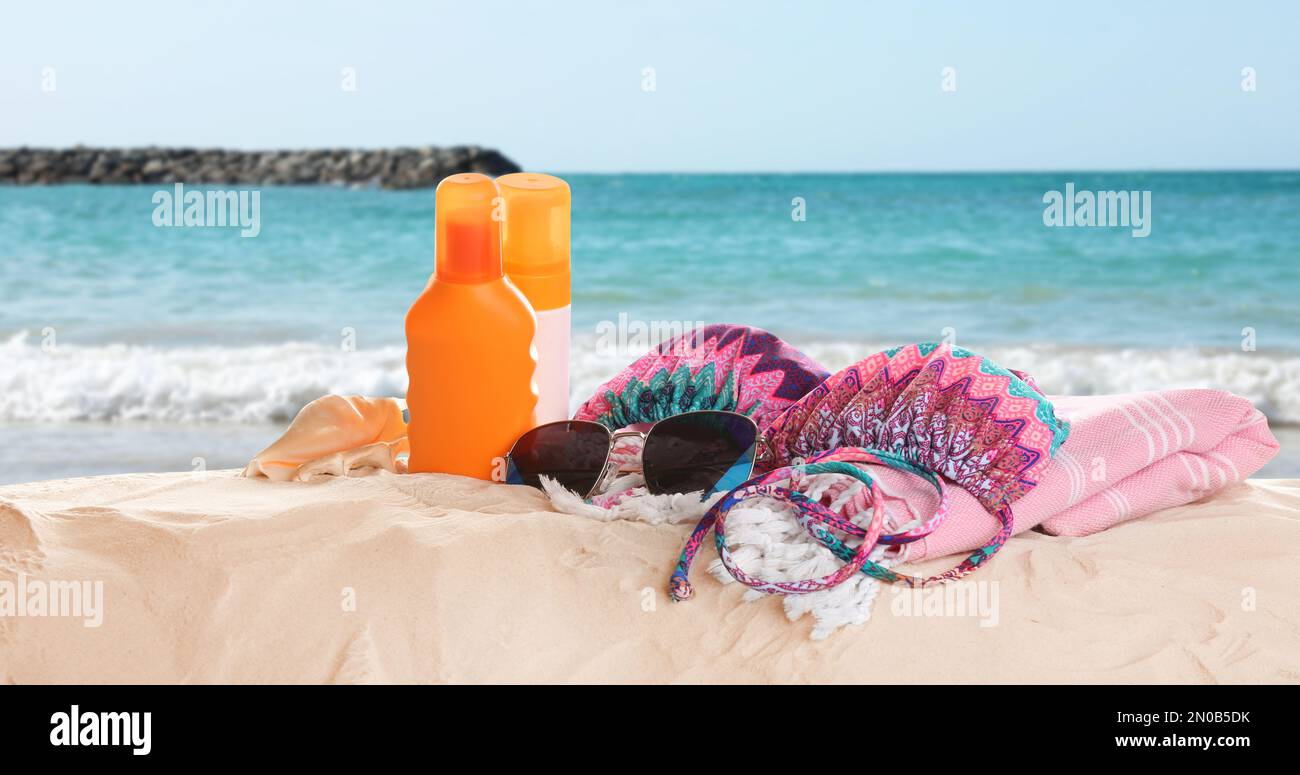 Différents accessoires de plage sur le sable près de la mer. Bannière Banque D'Images