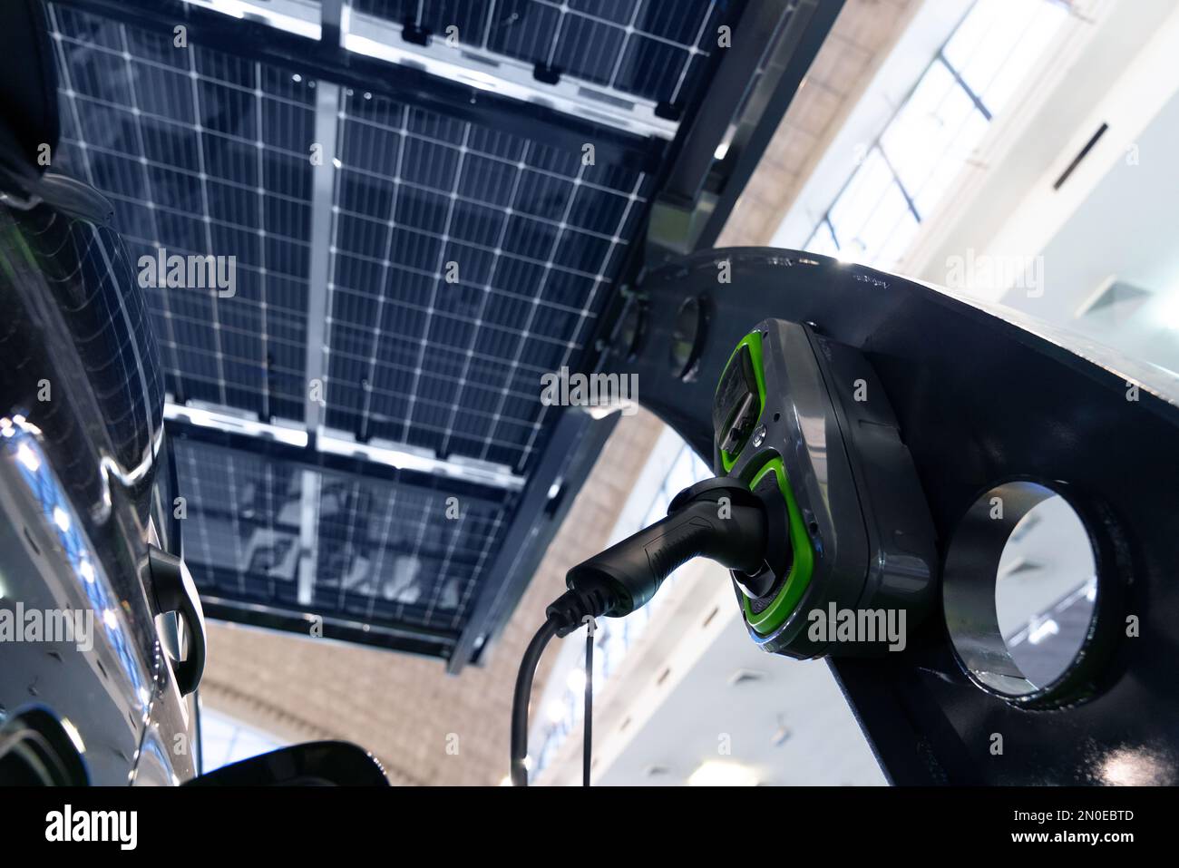 La voiture électrique est chargée à partir d'une station de charge qui prend l'énergie des panneaux solaires. Gros plan Banque D'Images