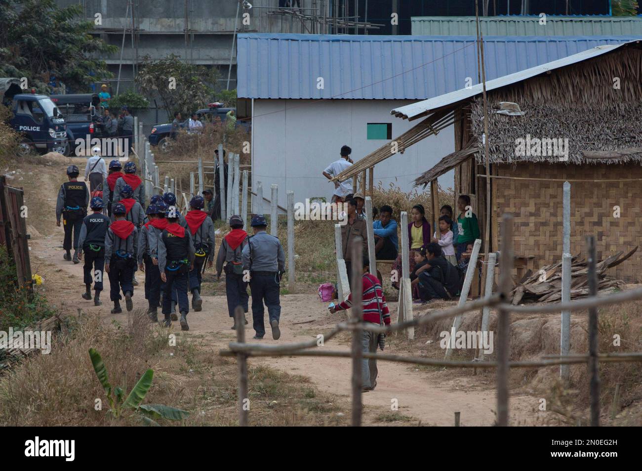 Residents who received notice to vacate their home from Myanmar's Ministry of Home Affairs, right, watch police officers walking past their house in Mingalardon, suburbs of Yangon, Myanmar, Monday, Jan. 25, 2016. About 10,000 living in 2000 houses in 560 acres adjoining a beer factory and owned by Myanmar military, were ordered to move out of their houses, resident Khin Soe Wai said. (AP Photo/ Gemunu Amarasinghe) Banque D'Images