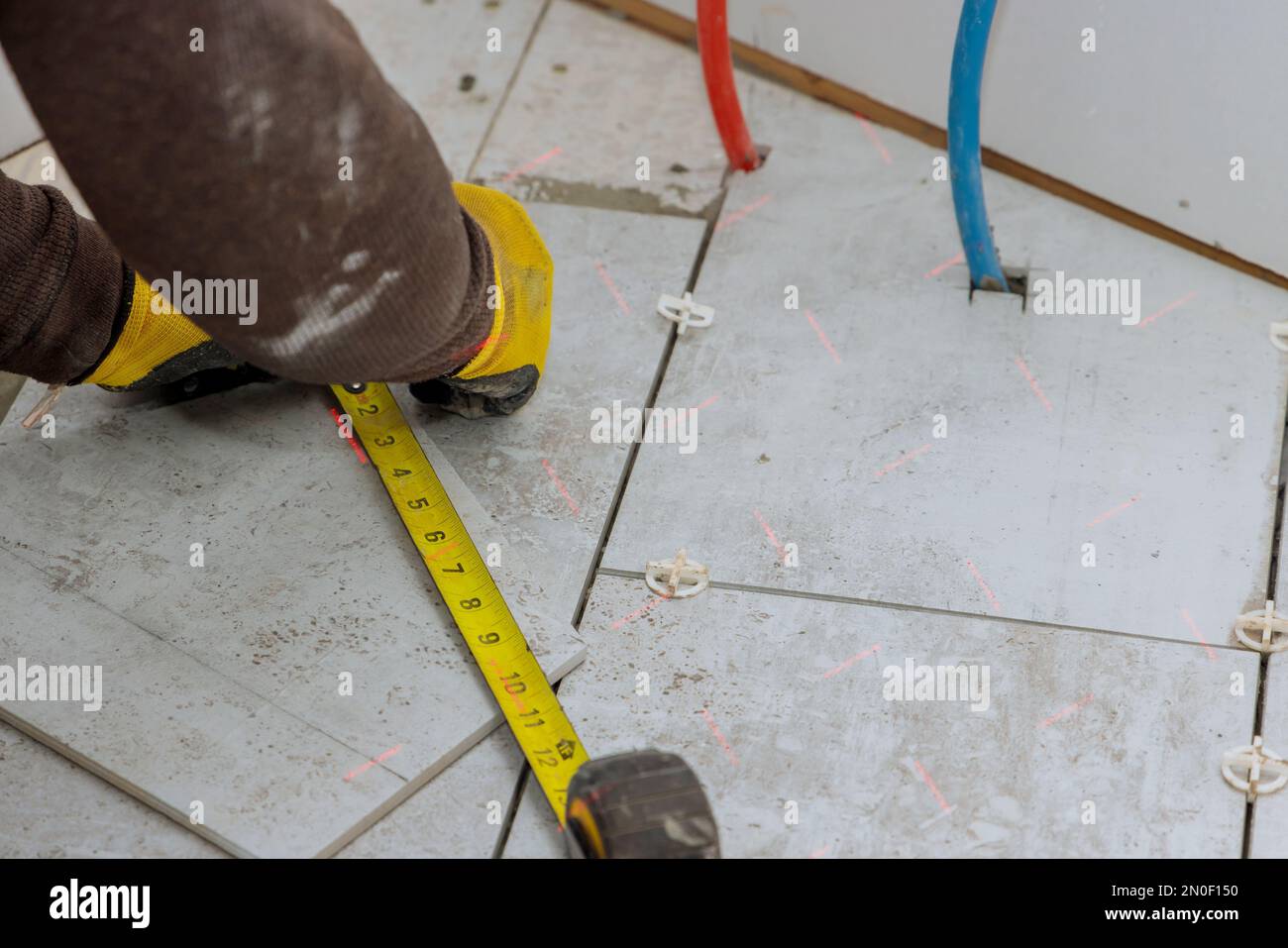 Lors de la préparation de la pose des carreaux de sol, l'entrepreneur mesure les carreaux de céramique avant qu'ils ne soient coupés en morceaux individuels Banque D'Images
