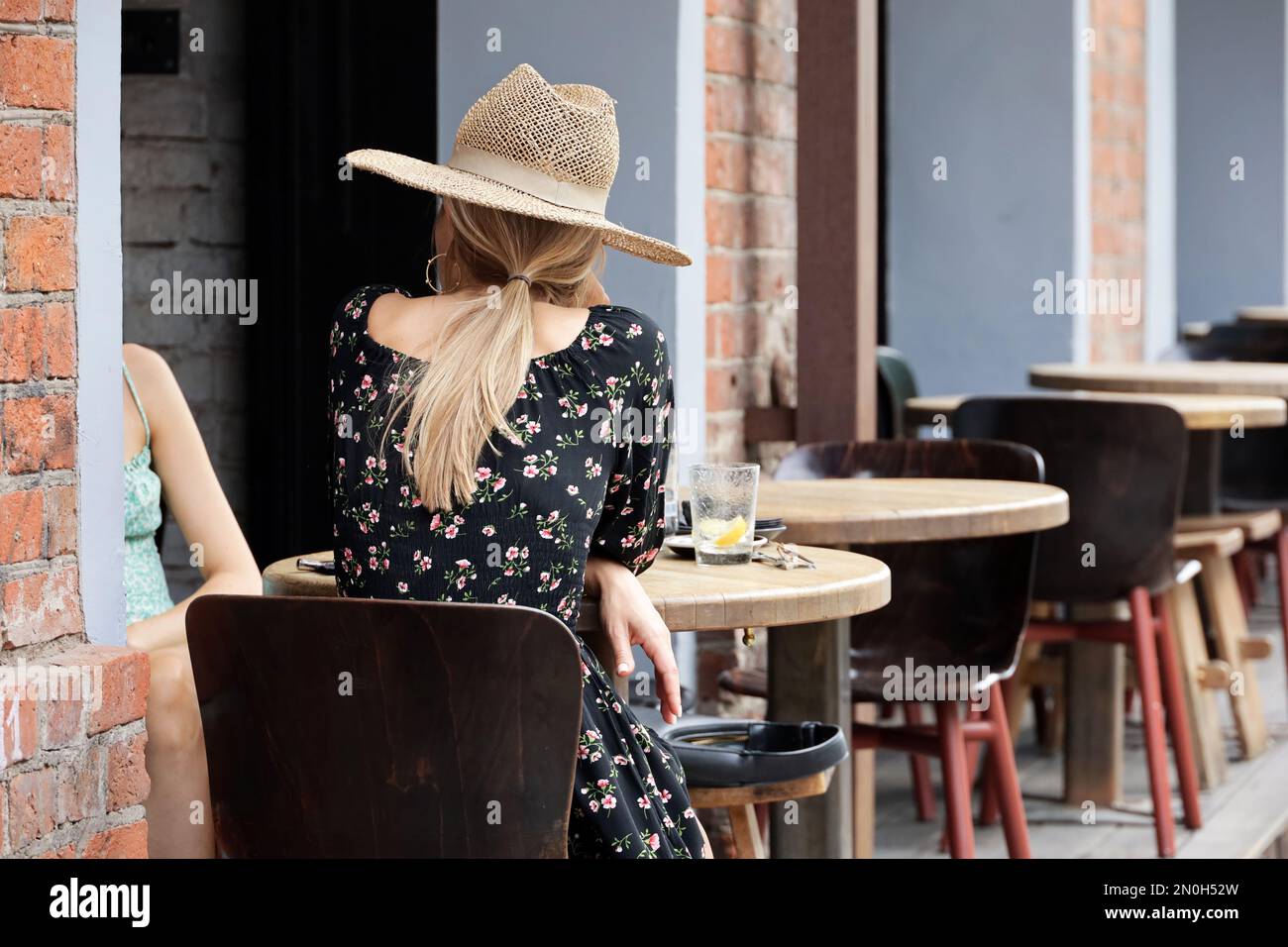 Deux filles parlent assis à une table en bois sur la terrasse du café de rue. L'amitié, la vie et les loisirs féminins dans la ville d'été Banque D'Images