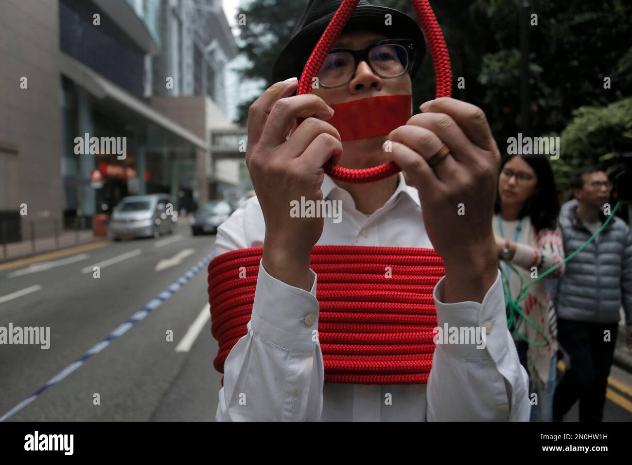 A local artist ties himself with a rope during a protest against the disappearances of booksellers in Hong Kong, Sunday, Jan. 10, 2016. Five men associated with a Hong Kong publisher known for books critical of China's leaders have vanished one by one in the last three months, alarming activists and deepening suspicions that mainland authorities are squeezing free expression in the enclave. (AP Photo/Vincent Yu) Banque D'Images