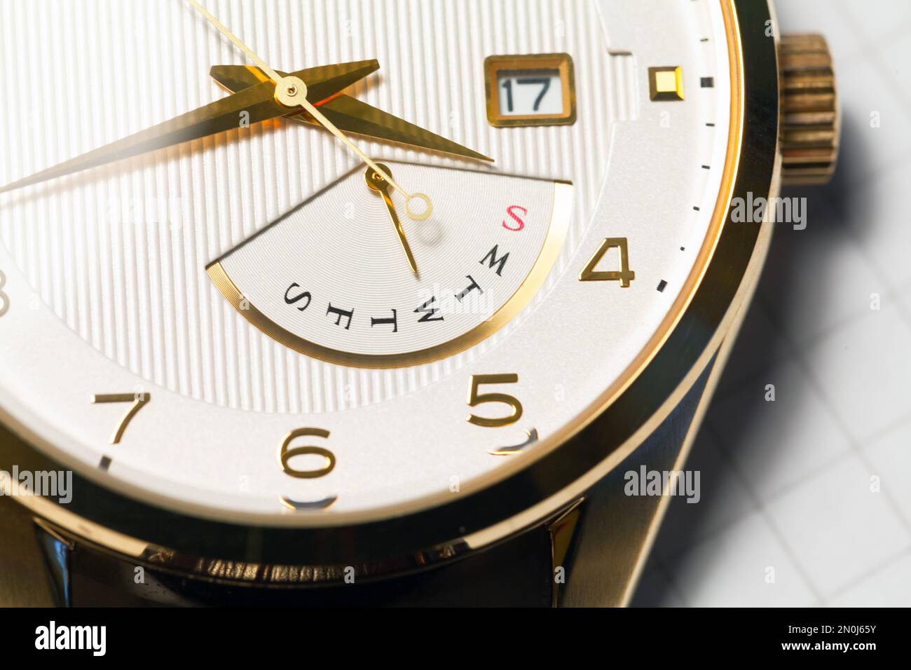 Montre-bracelet classique blanche avec mains dorées et indicateur de jour de la semaine rétrograde, macro photo avec mise au point sélective Banque D'Images