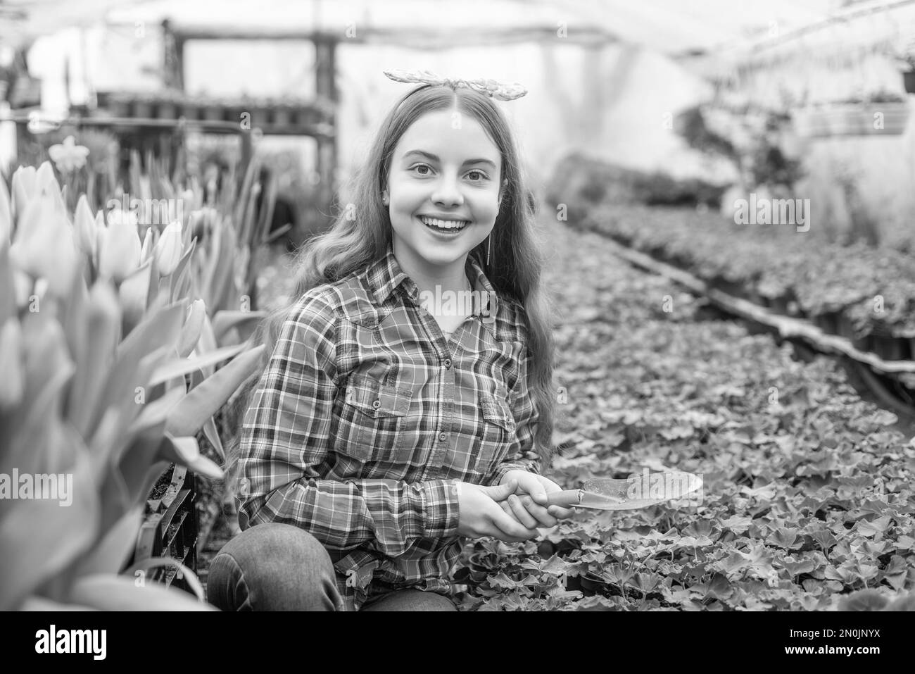 bonne adolescente fleuriste de l'adolescence planter des plantes de pot en serre, printemps Banque D'Images