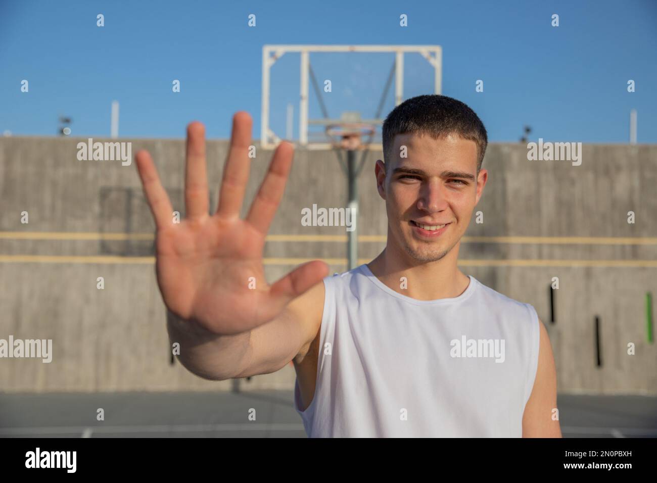 Un jeune joueur de basket-ball sur un terrain de basket-ball montre sa paume et ses sourires Banque D'Images