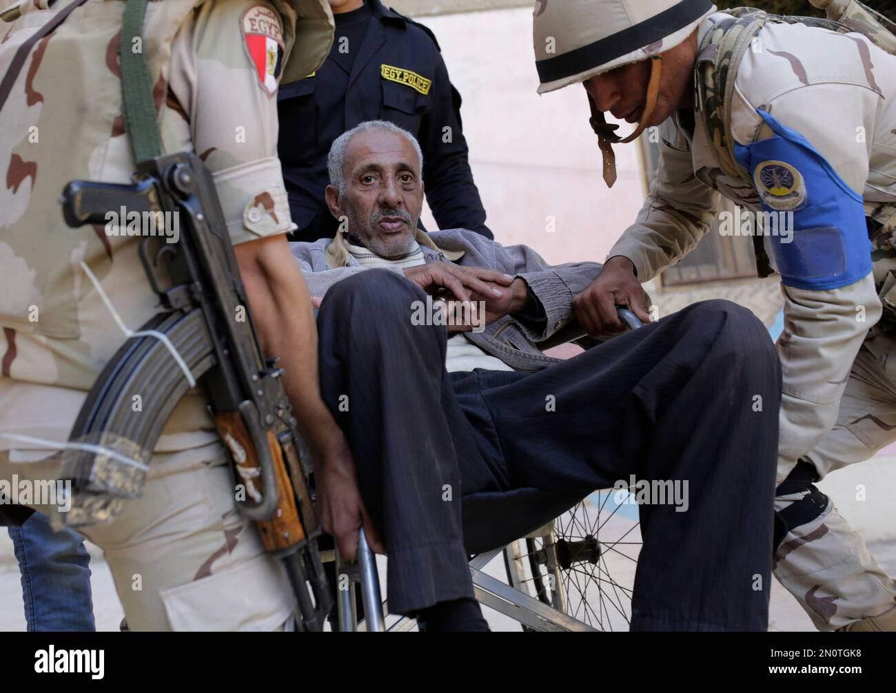 Egyptian disabled man, Yehya Yousef, 63, is carried by soldiers as he prepares to vote at a polling station during the second day of the runoff to the second phase of the parliamentary election in Cairo, Egypt, Wednesday, Dec. 2, 2015. (AP Photo/Amr Nabil) Banque D'Images