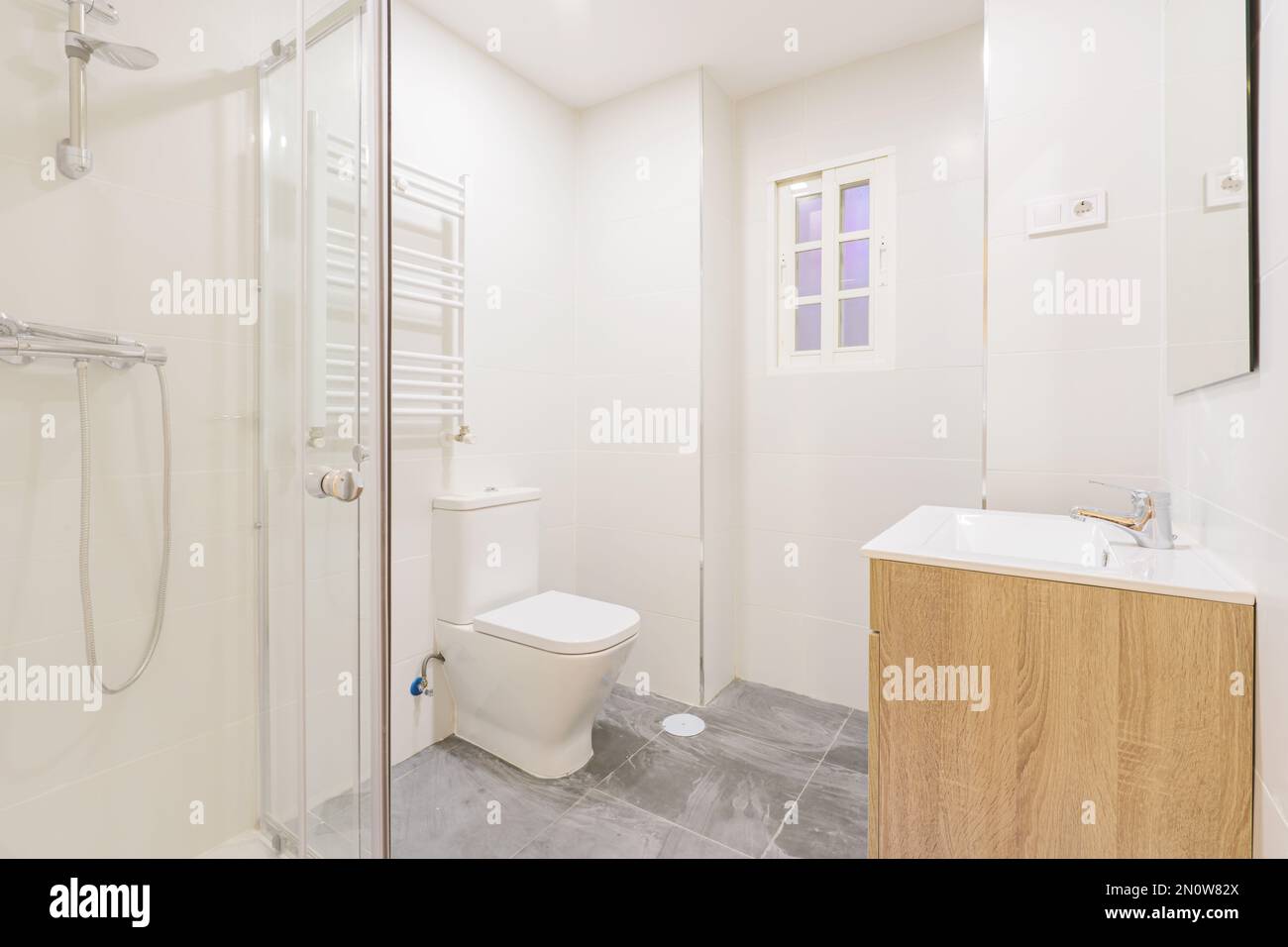 salle de bains avec lavabo en bois sous un miroir mural sans cadre, douche à l'italienne avec écrans, porte-serviettes chauffant et portes en bois blanc Banque D'Images