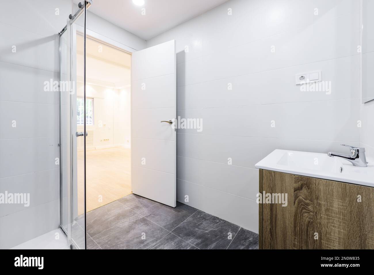 salle de bains avec lavabo en bois sous le miroir mural sans cadre, cabine de douche avec écrans Banque D'Images