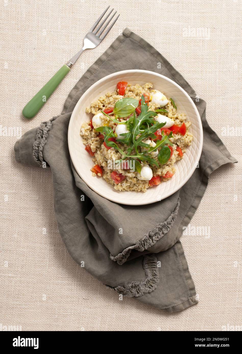 Boulgour avec tomates cerises, mozzarella arugula, feuilles de basilic et huile d'olive. Un plat méditerranéen, sain et végétarien. Banque D'Images