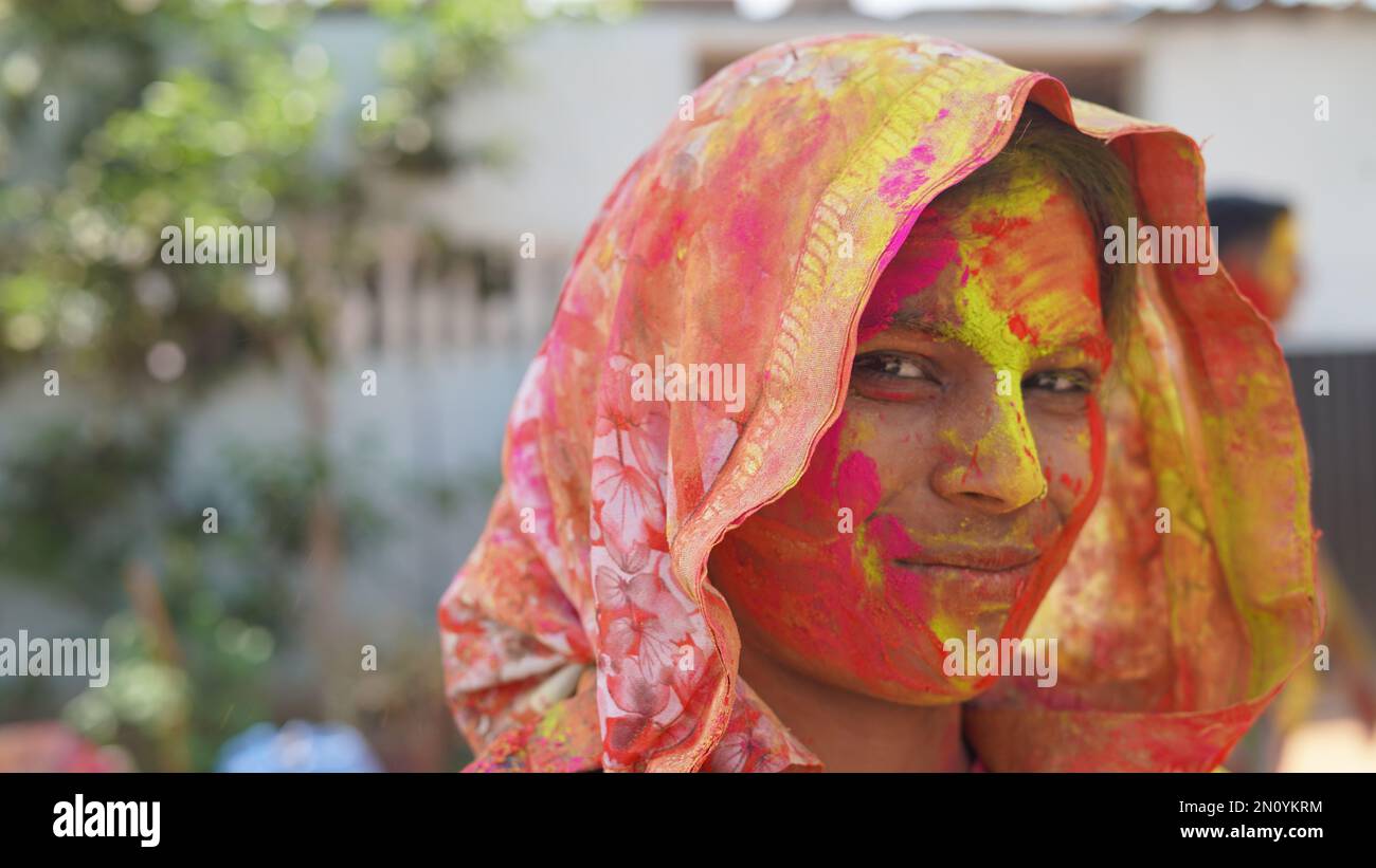 Jeune femme indienne avec de la poudre de couleur dans sa main et avec le visage coloré avec le gulal pour le festival des couleurs Holi Banque D'Images