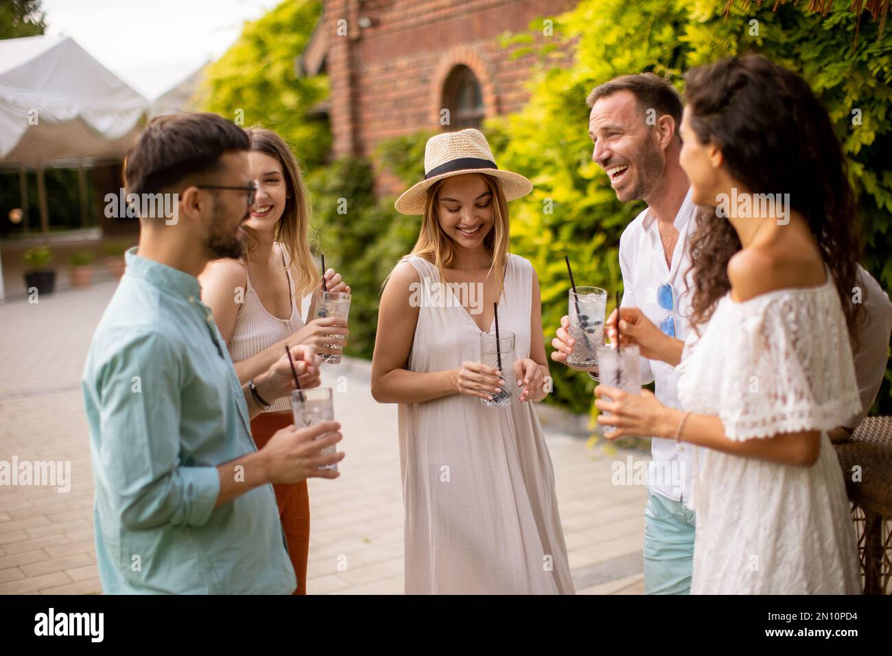 Un groupe de jeunes se rassemblent à l'extérieur pour profiter de la compagnie de l'autre et des verres rafraîchissants de limonade Banque D'Images