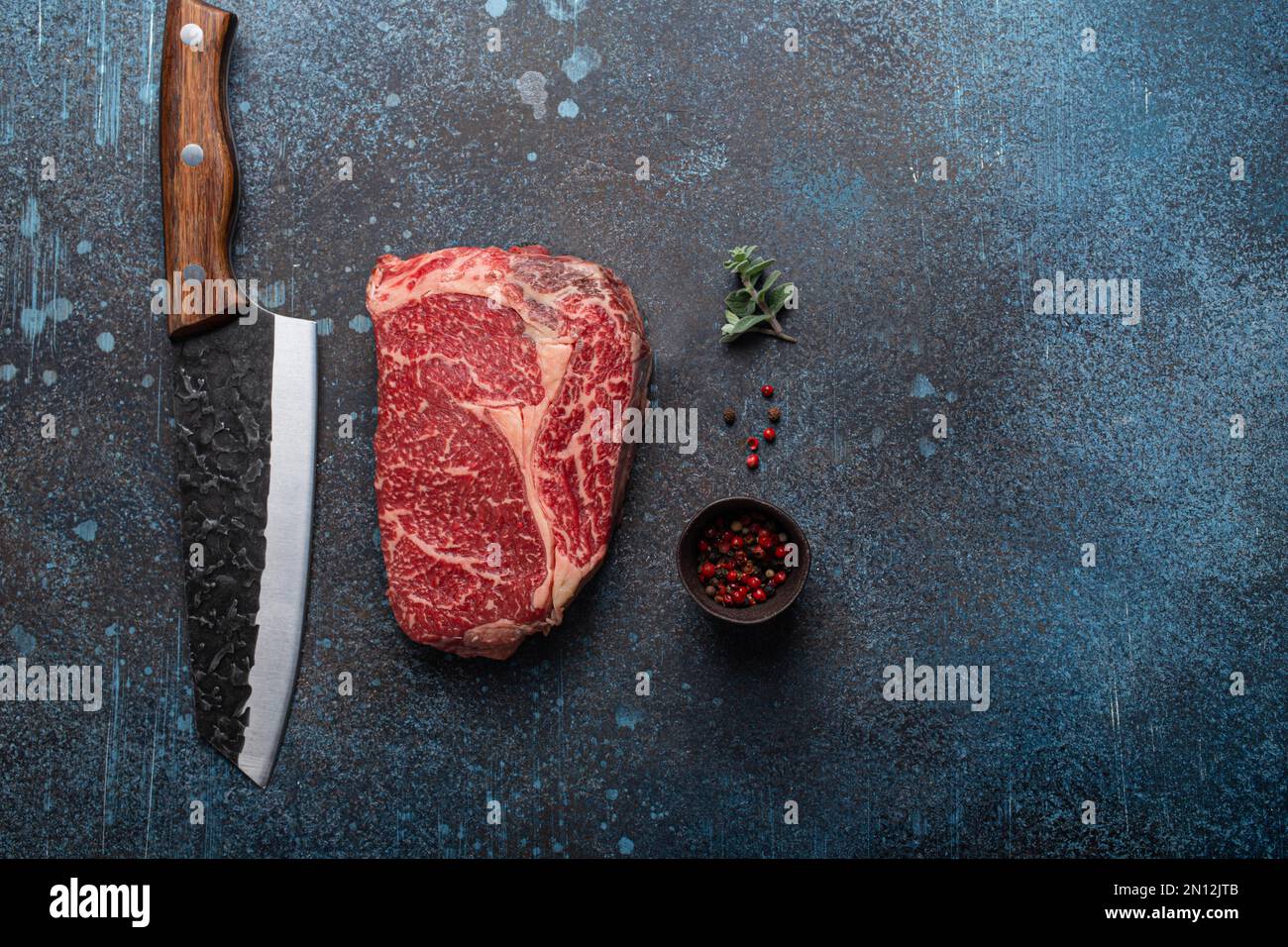 Bœuf à la viande cru bœuf marbré steak de première qualité Ribeye sur fond rustique de table de cuisine en béton d'en haut avec un grand couteau et des épices, beefsteak concept espace Banque D'Images