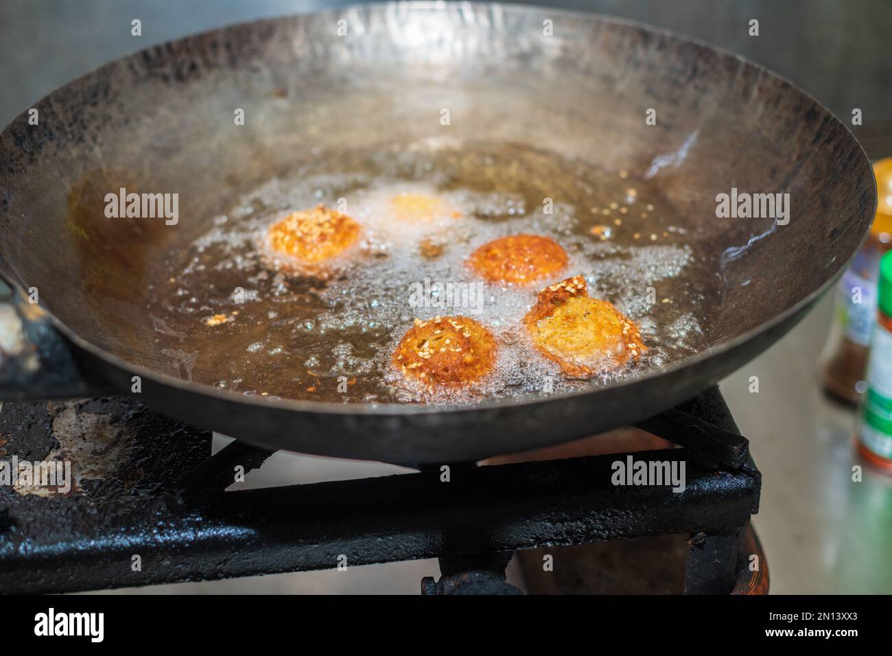 Des boulettes de falafel à friture profonde dans un wok, des huiles de cuisson chaudes bouillant, et des boulettes de falafel ont tourné une couleur dorée Banque D'Images