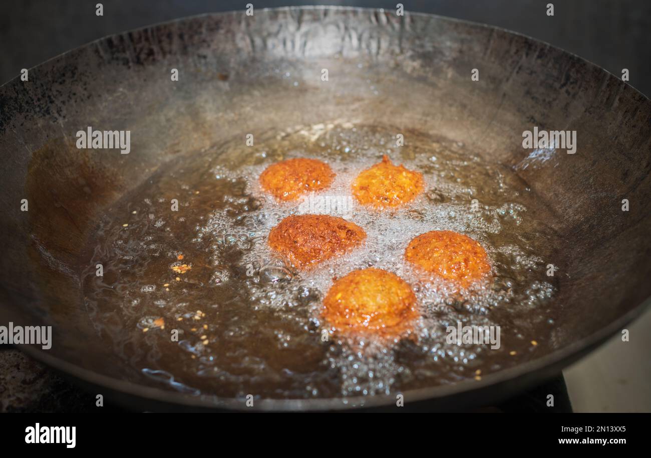 Des boulettes de falafel à friture profonde dans un wok, des huiles de cuisson chaudes bouillant, et des boules de falafel ont changé de couleur dorée. Banque D'Images