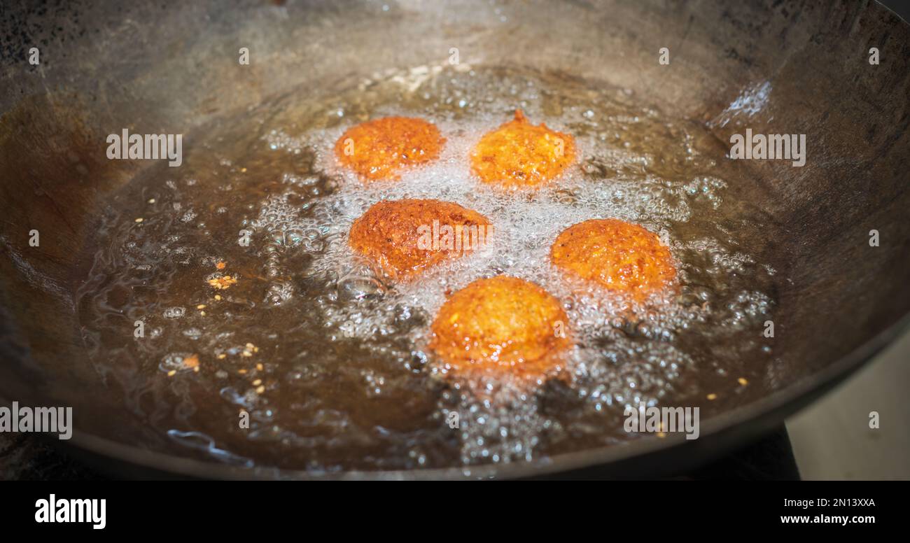 Boulettes de falafel à friture profonde dans le wok, les huiles de cuisson chaudes bouillant et les boulettes de falafel sont de couleur dorée Banque D'Images
